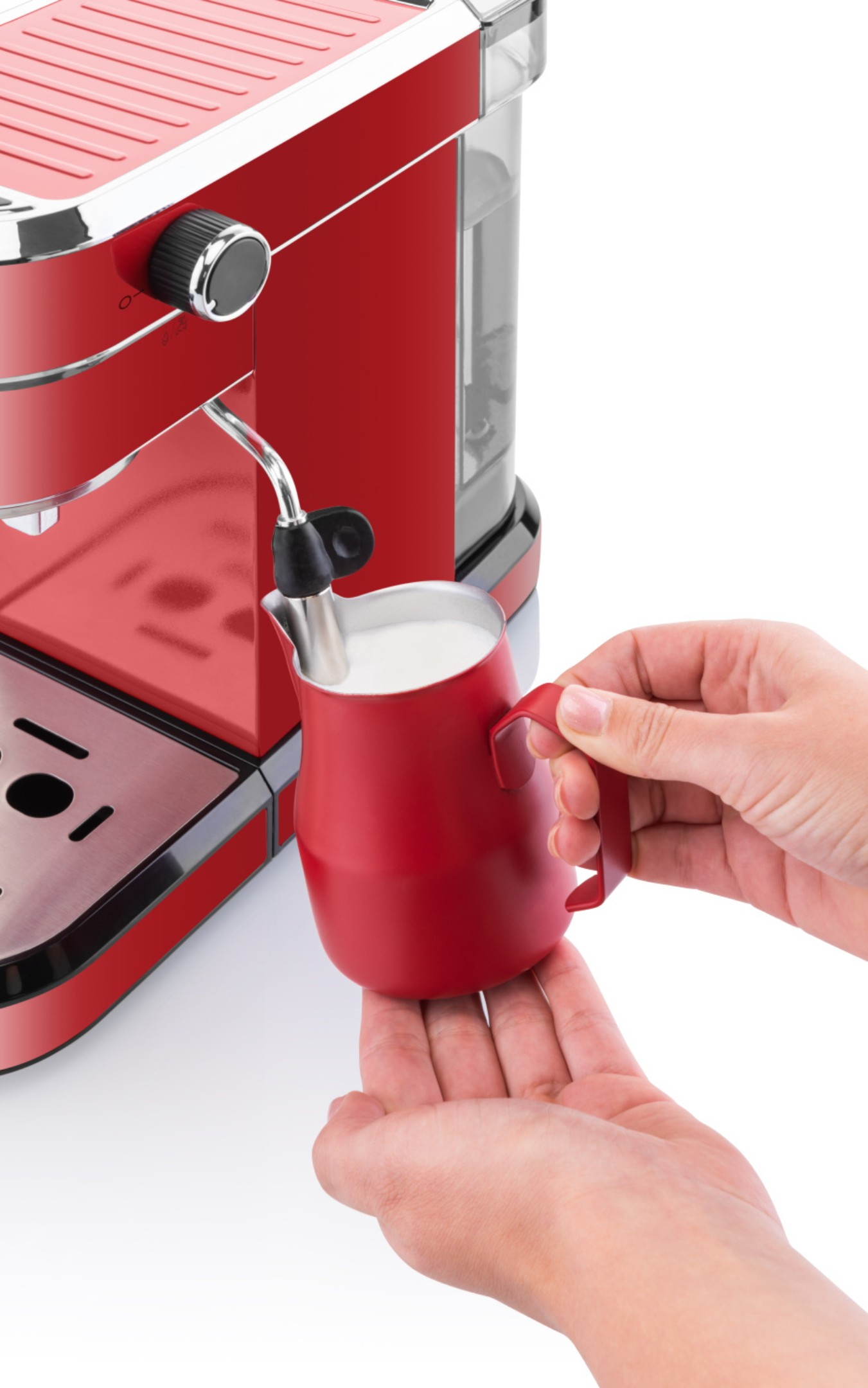 Osoba trzymająca czerwony dzbanek do spieniania mleka, z ekspresem do kawy.