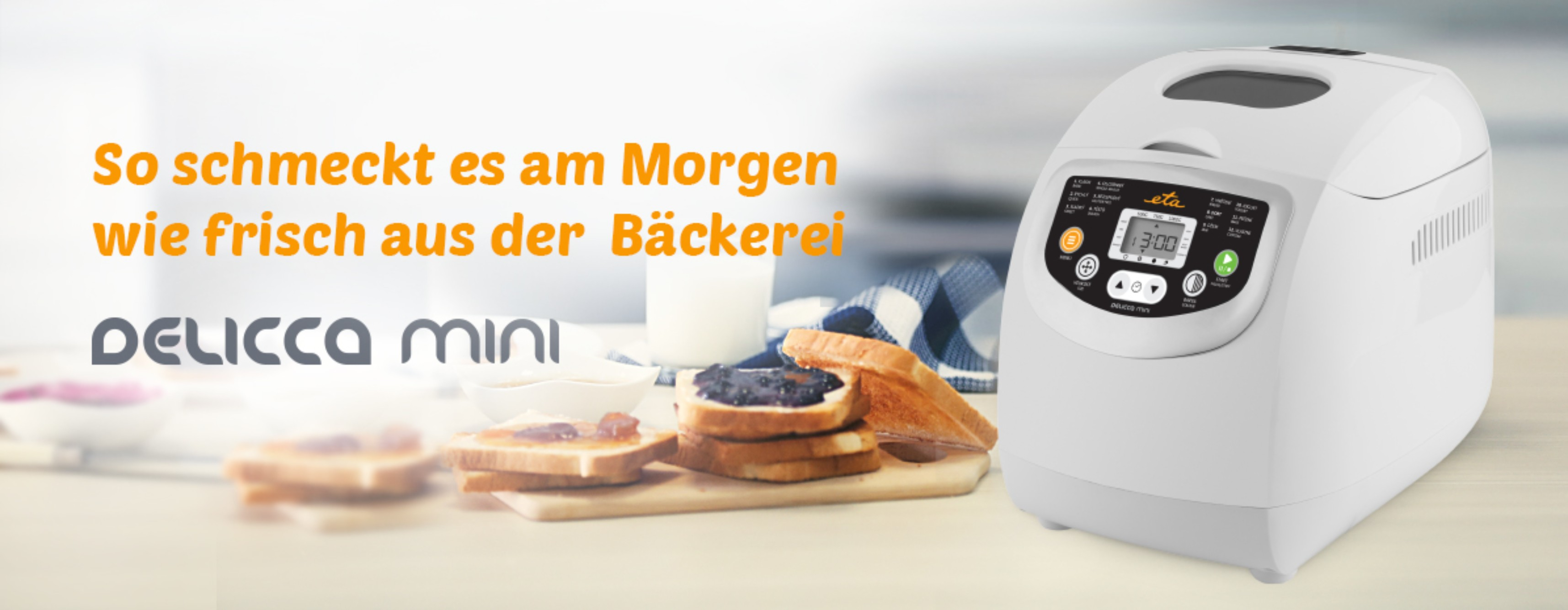 Weißer Brotbackautomat mit Toast, Marmelade und einem Milchglas auf einem Tisch. Text: So schmeckt es am Morgen.