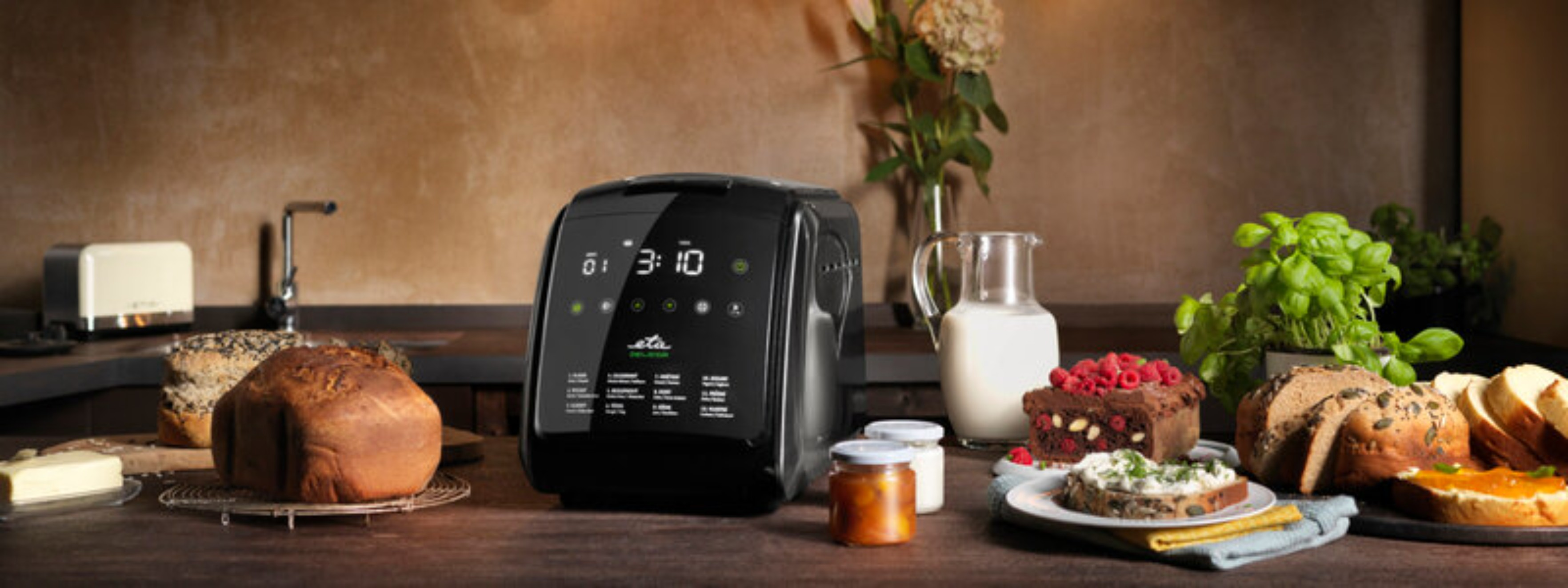 Maszyna do pieczenia chleba z chlebem, owocami i innymi produktami na drewnianym stole.