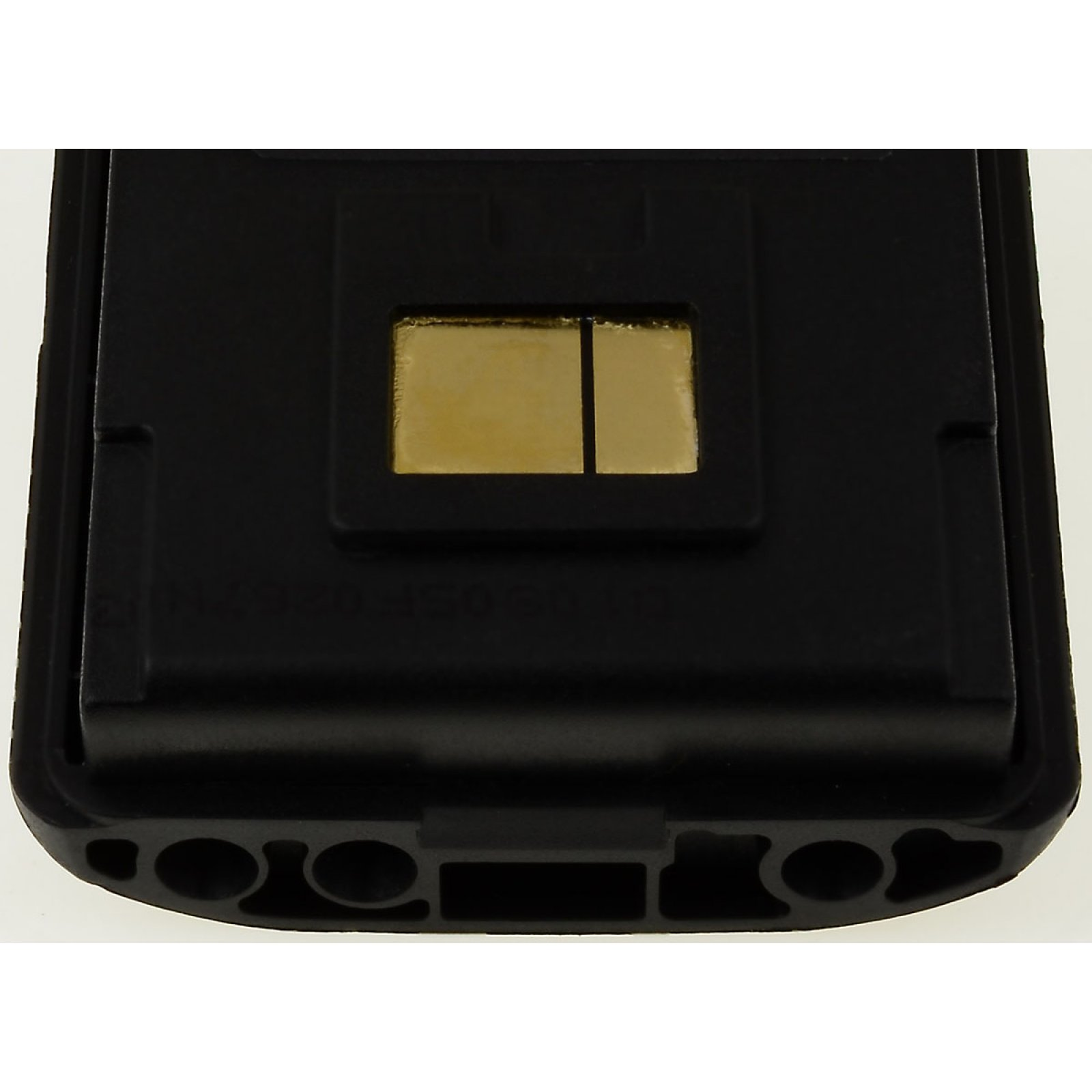 Dispositivo negro, primer plano. Contiene una pieza rectangular dorada. El dispositivo está sobre una superficie blanca.