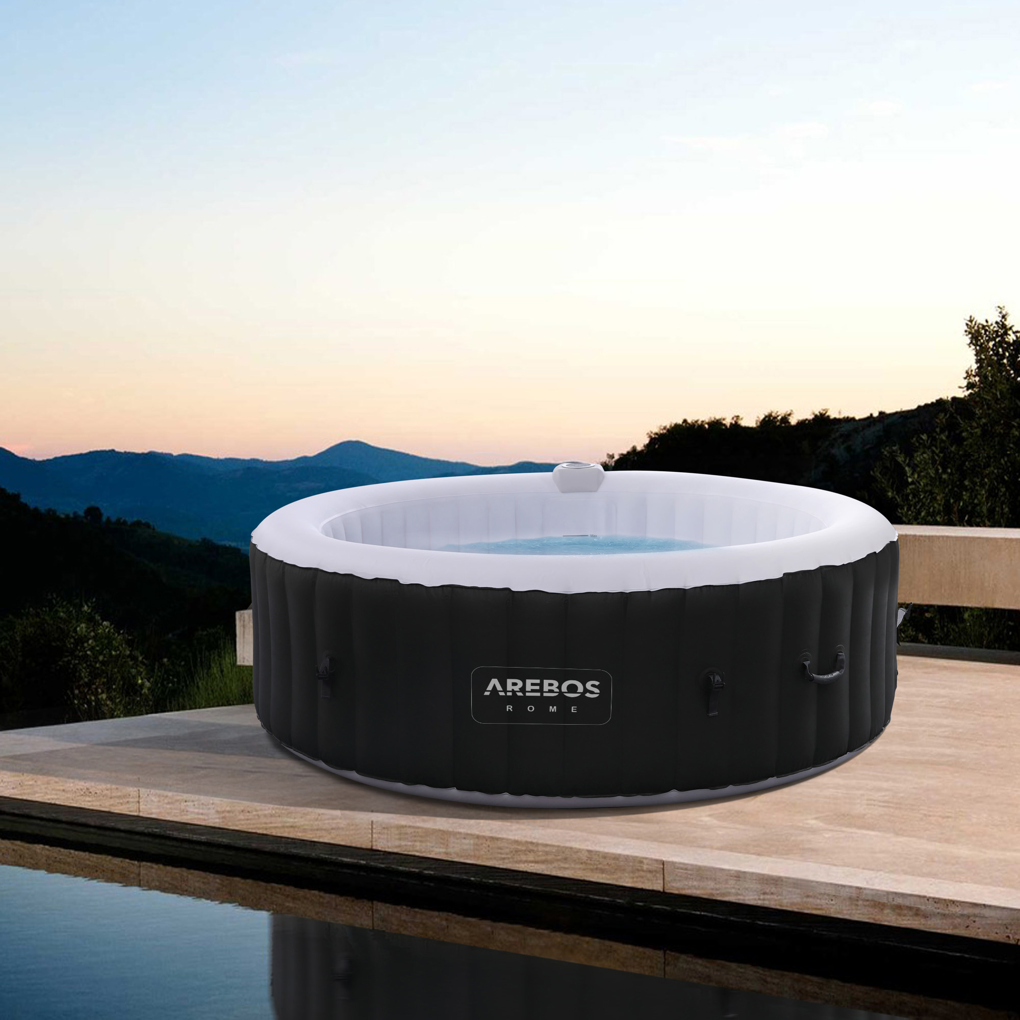 Schwarzer und weißer Whirlpool auf Holzterrasse, Sonnenuntergang im Hintergrund.