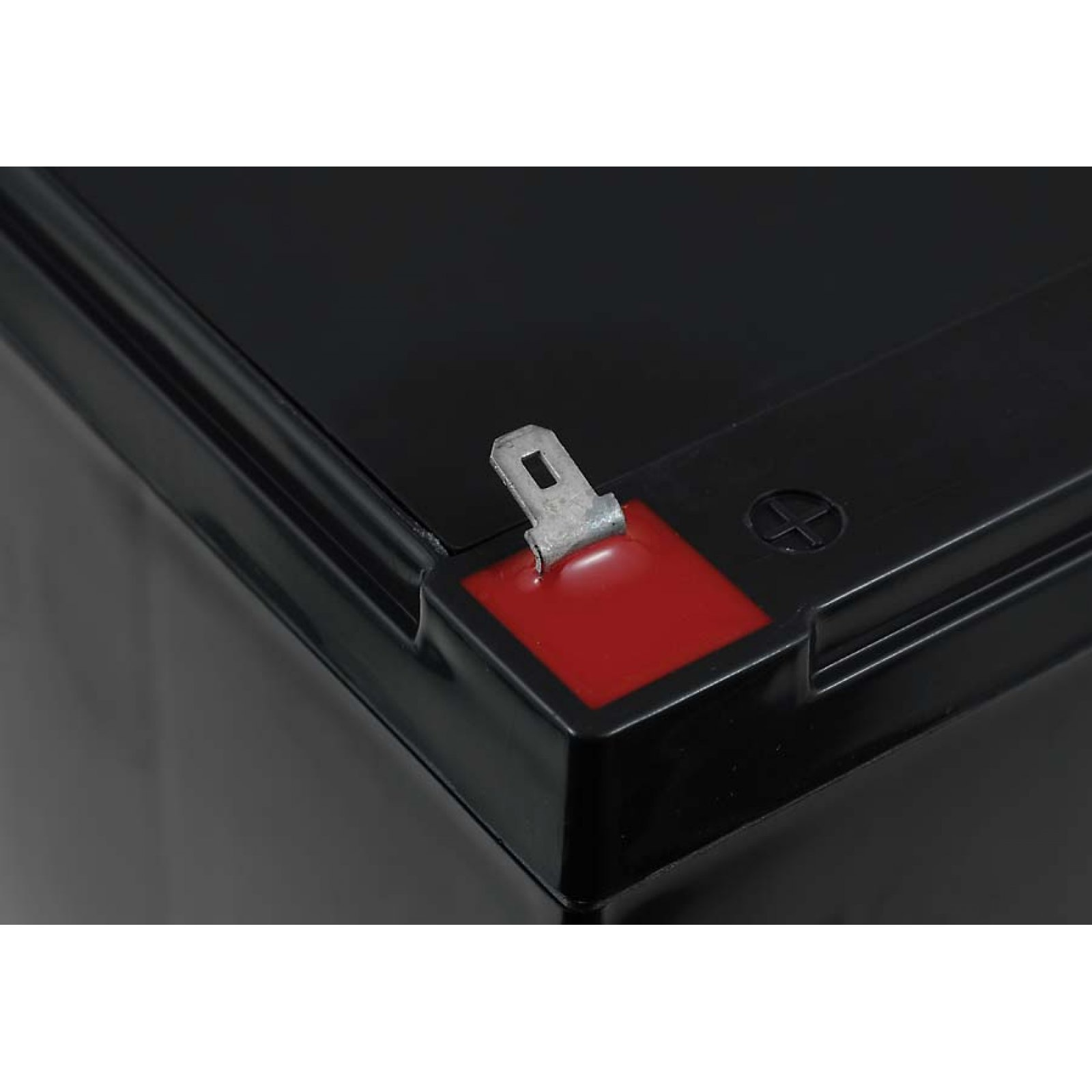 Primer plano de un terminal de batería negro con una marca roja y una pinza metálica.