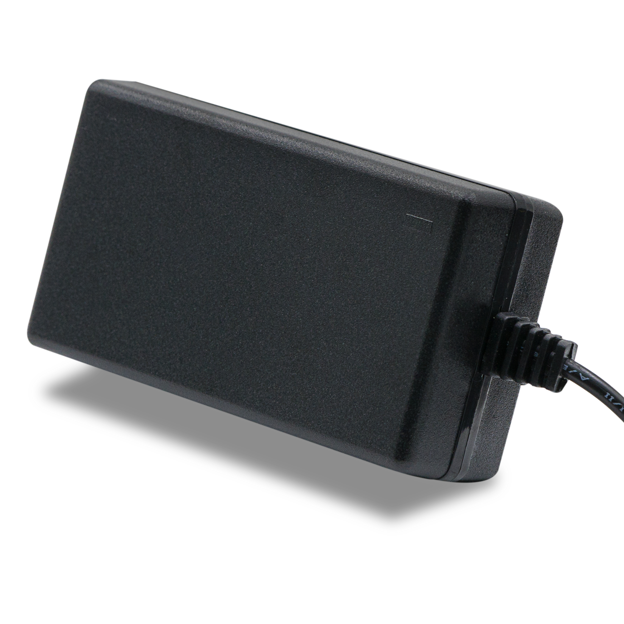 Schwarzes Netzteil mit schwarzem Kabel. Es liegt auf einer weißen Oberfläche.
