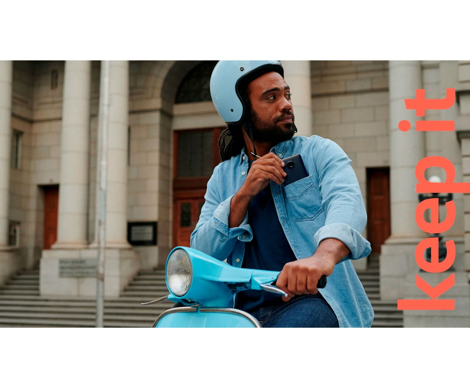 Mężczyzna na skuterze z telefonem w kieszeni, tło miejskie, tekst 'keep it'.