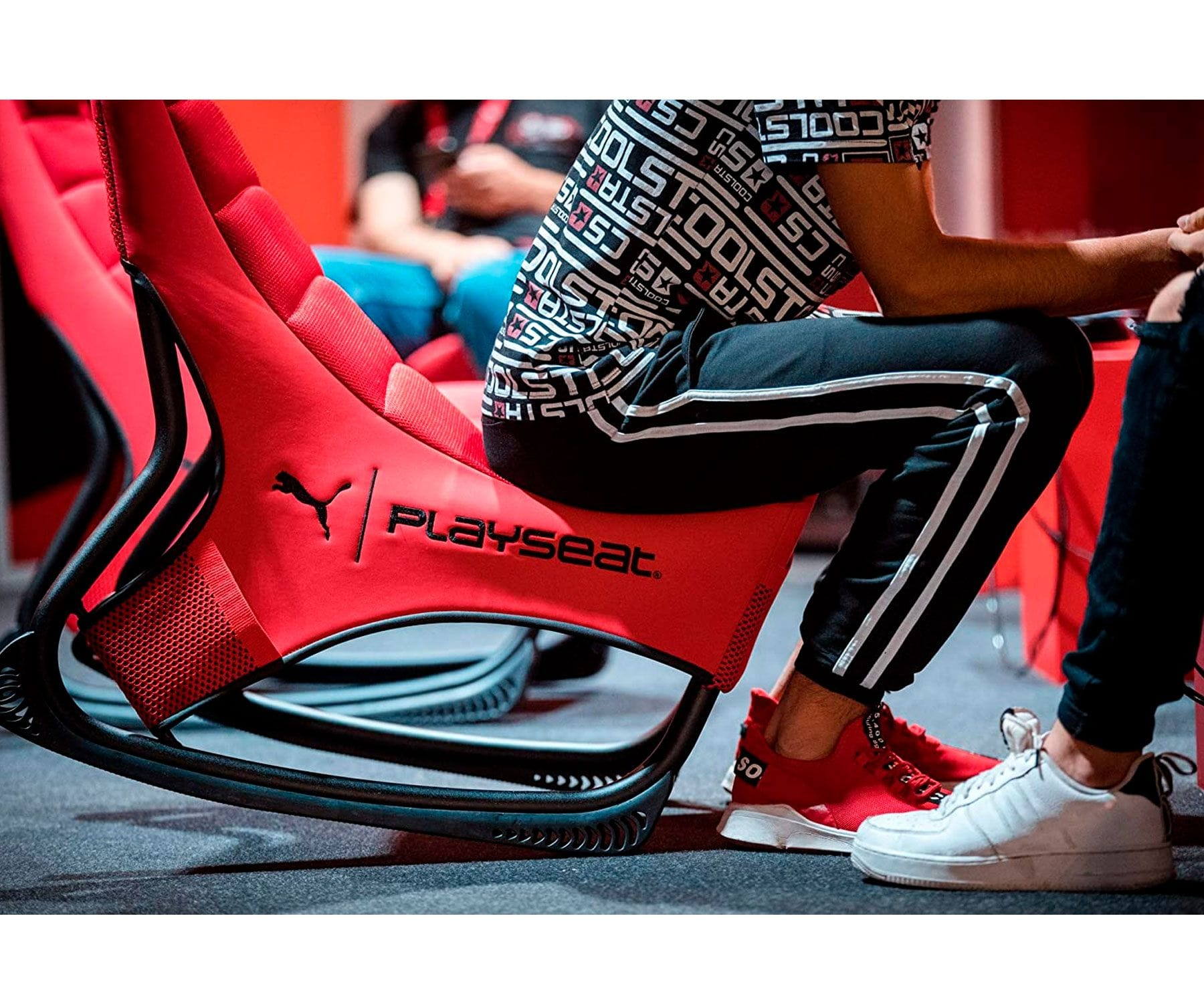 Persoon zit in een rode Puma gaming stoel.