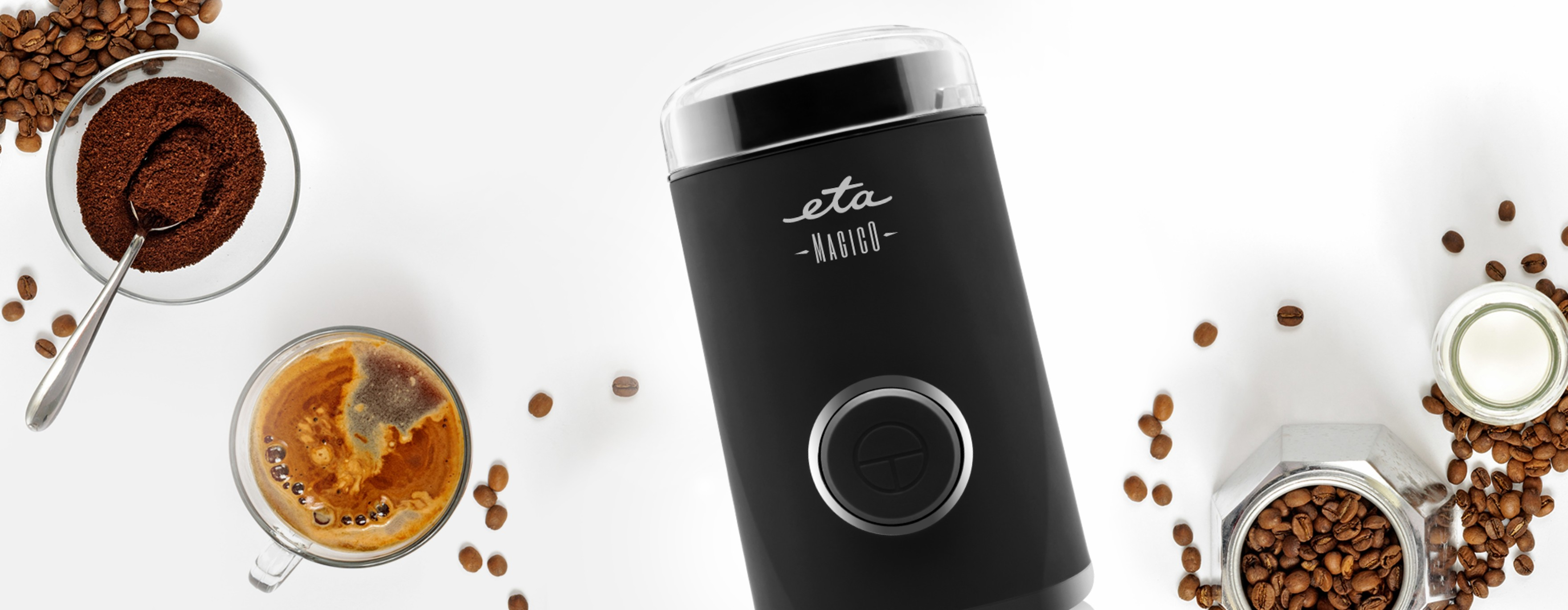 Kaffeemühle mit Kaffeesatz, Bohnen und einer Tasse Kaffee auf weißem Hintergrund.