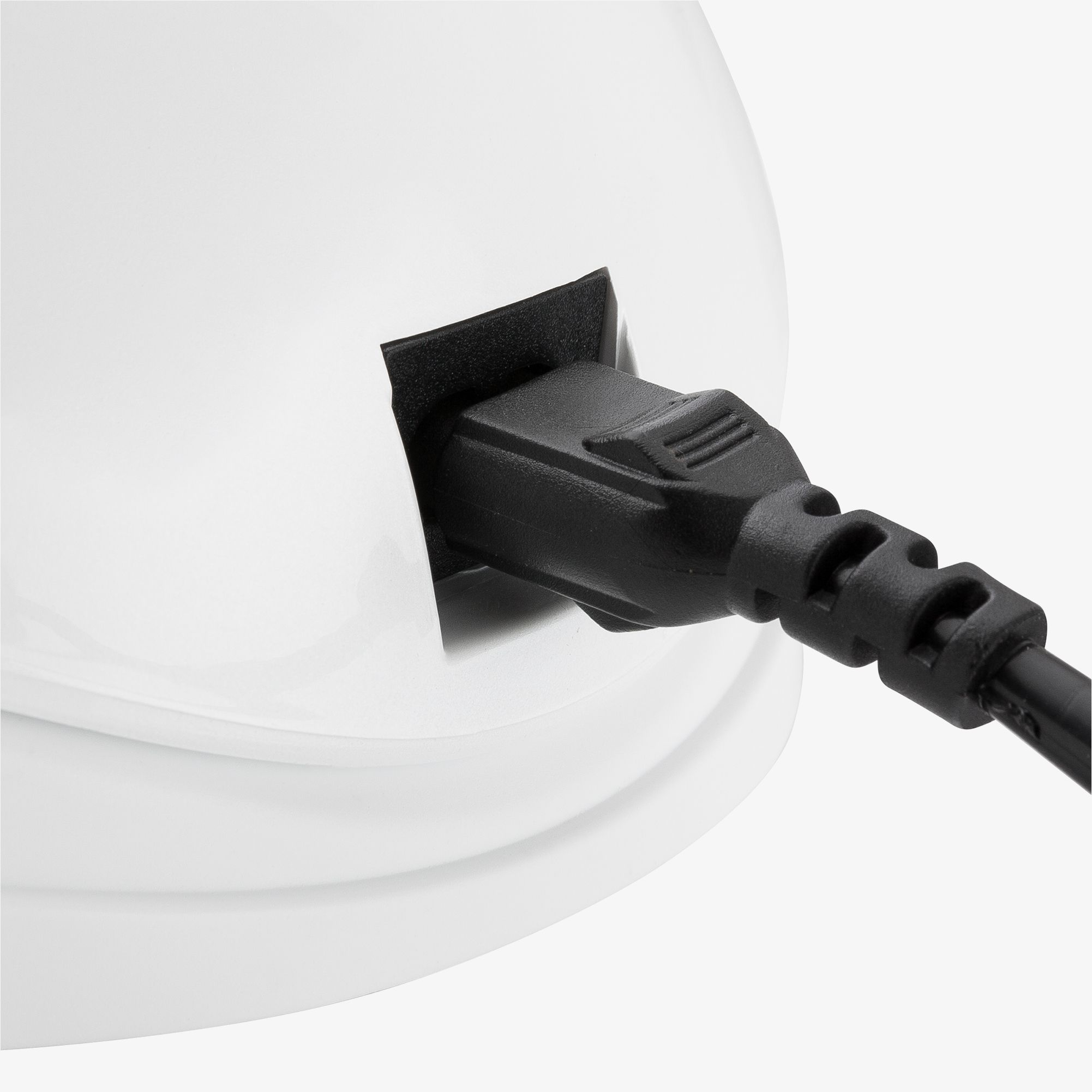 Schwarzes Netzkabel in ein weißes Gerät gesteckt, Nahaufnahme.