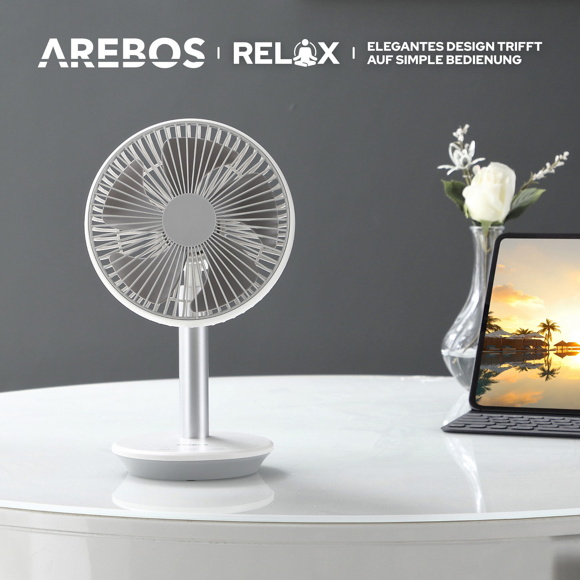 Weißer und silberner Ventilator auf einem Tisch mit Laptop und Vase.