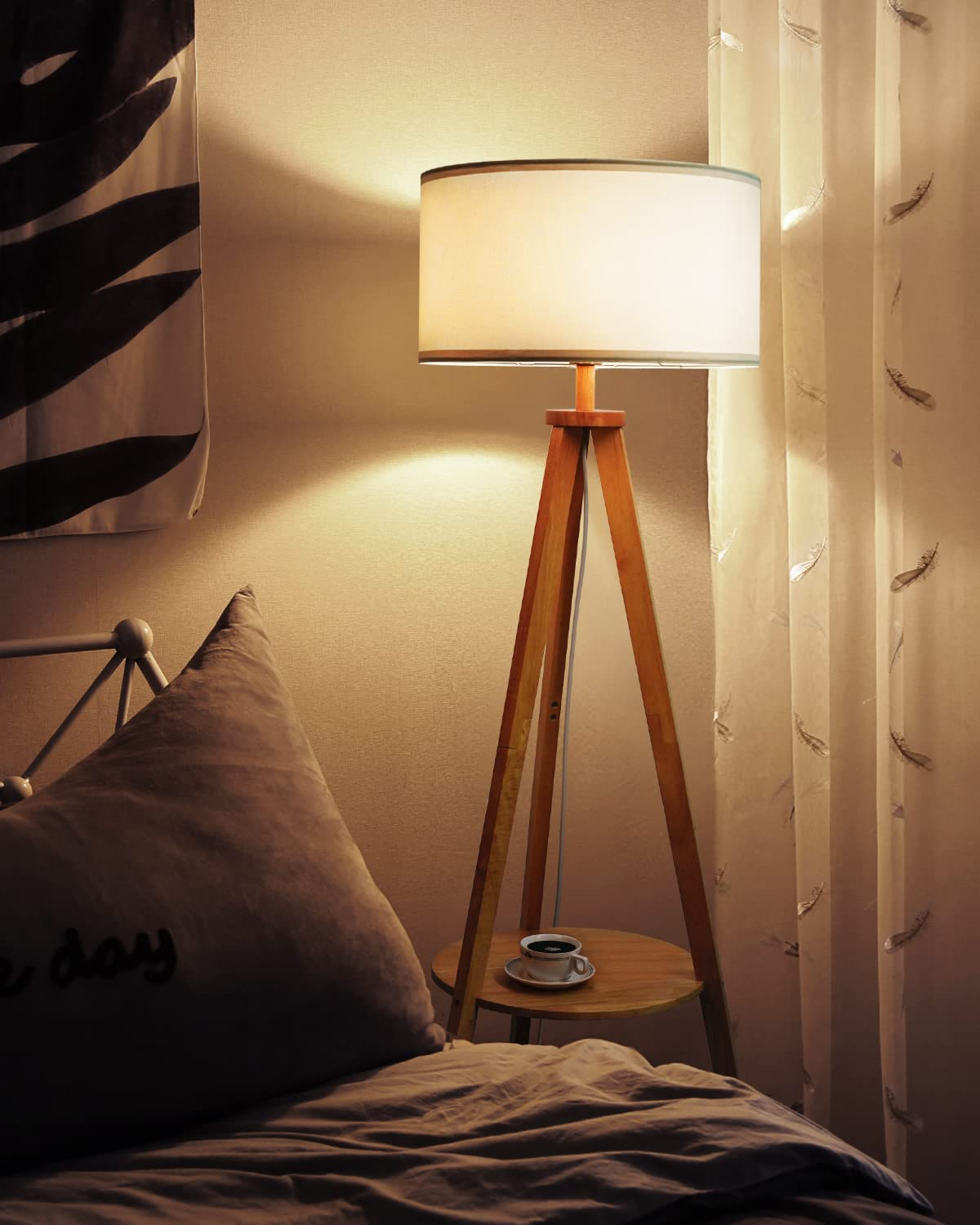 Scena di camera da letto con una lampada a treppiede in legno, un letto e un cuscino.