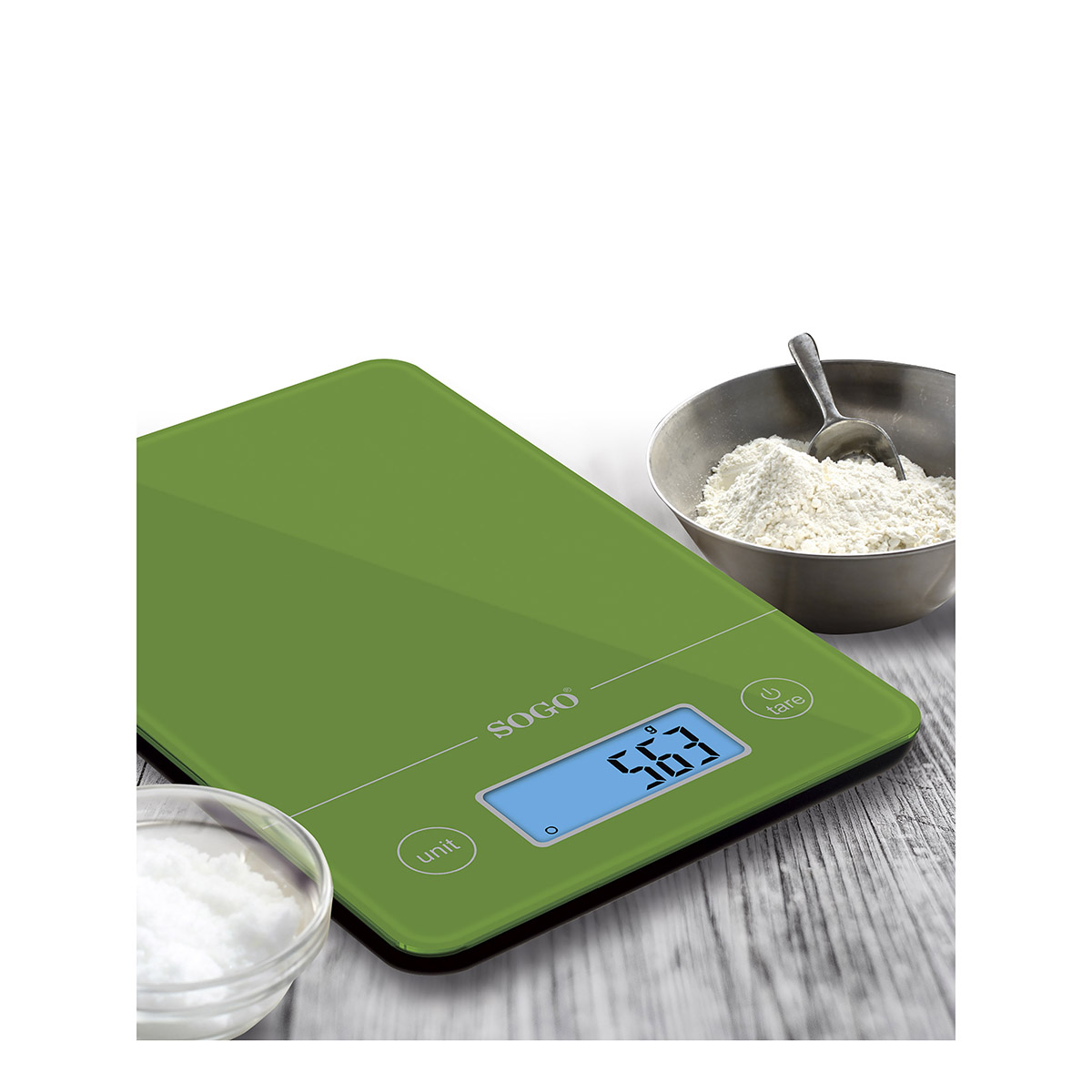 Una báscula de cocina verde muestra 563 gramos. Un cuenco de harina y un cuenco pequeño de polvo blanco están cerca.