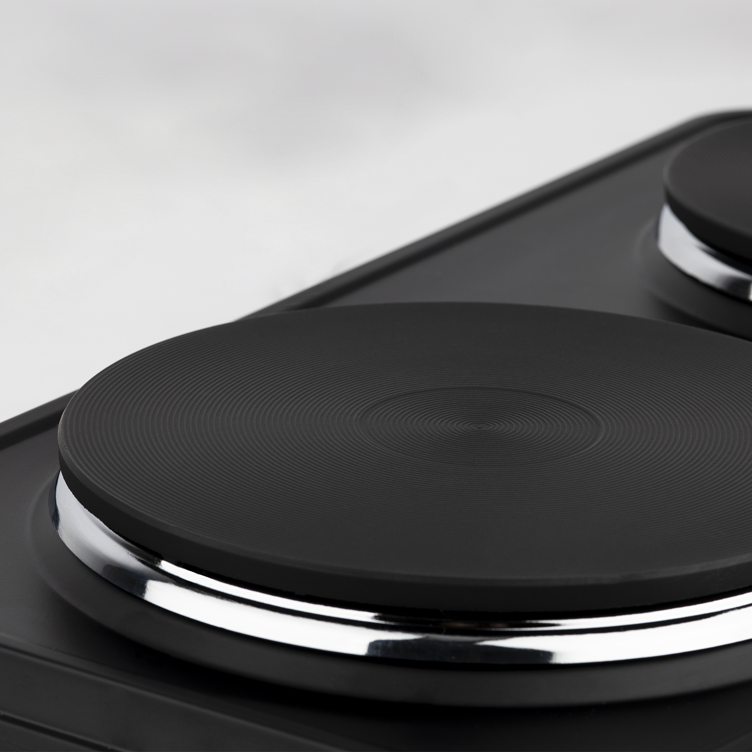 Zbliżenie dwóch czarnych palników elektrycznych z metalowymi, srebrnymi obwódkami.