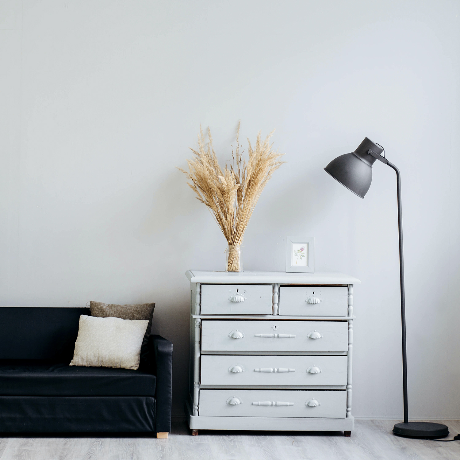 Salon z sofą, komodą, lampą i dekoracjami. Białe tło ściany.