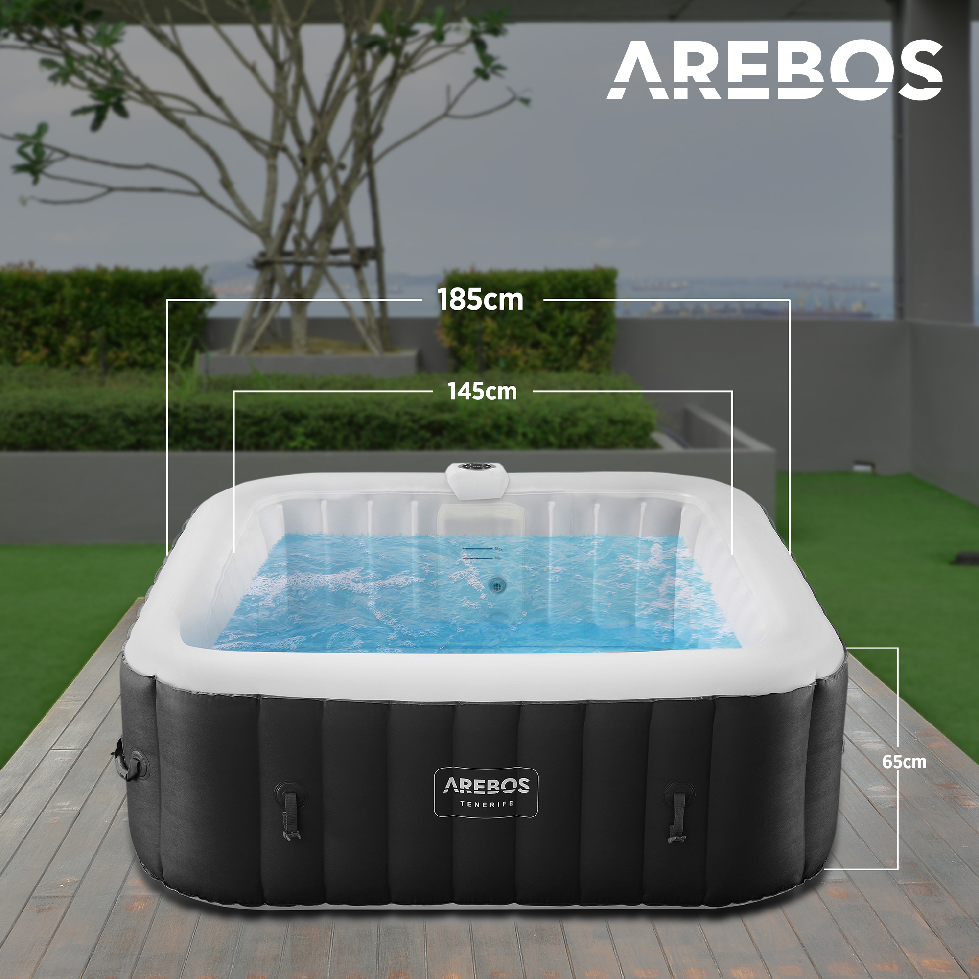 Ein aufblasbarer Whirlpool auf einer Holzterrasse, mit Wasser darin. Messetiketten sind vorhanden. Der Hintergrund ist ein Stadtblick.