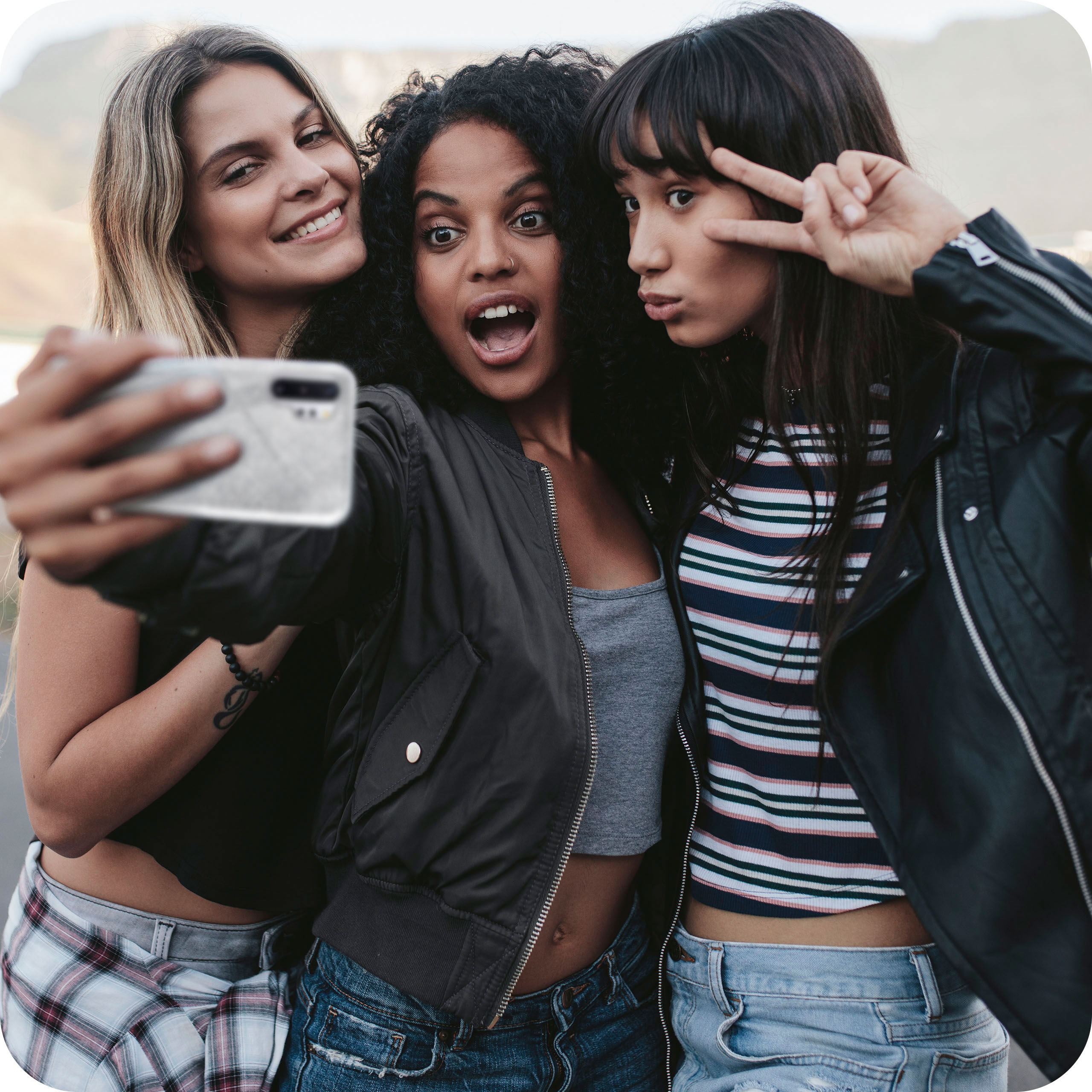 Drei Frauen machen ein Selfie, eine macht das Peace-Zeichen.