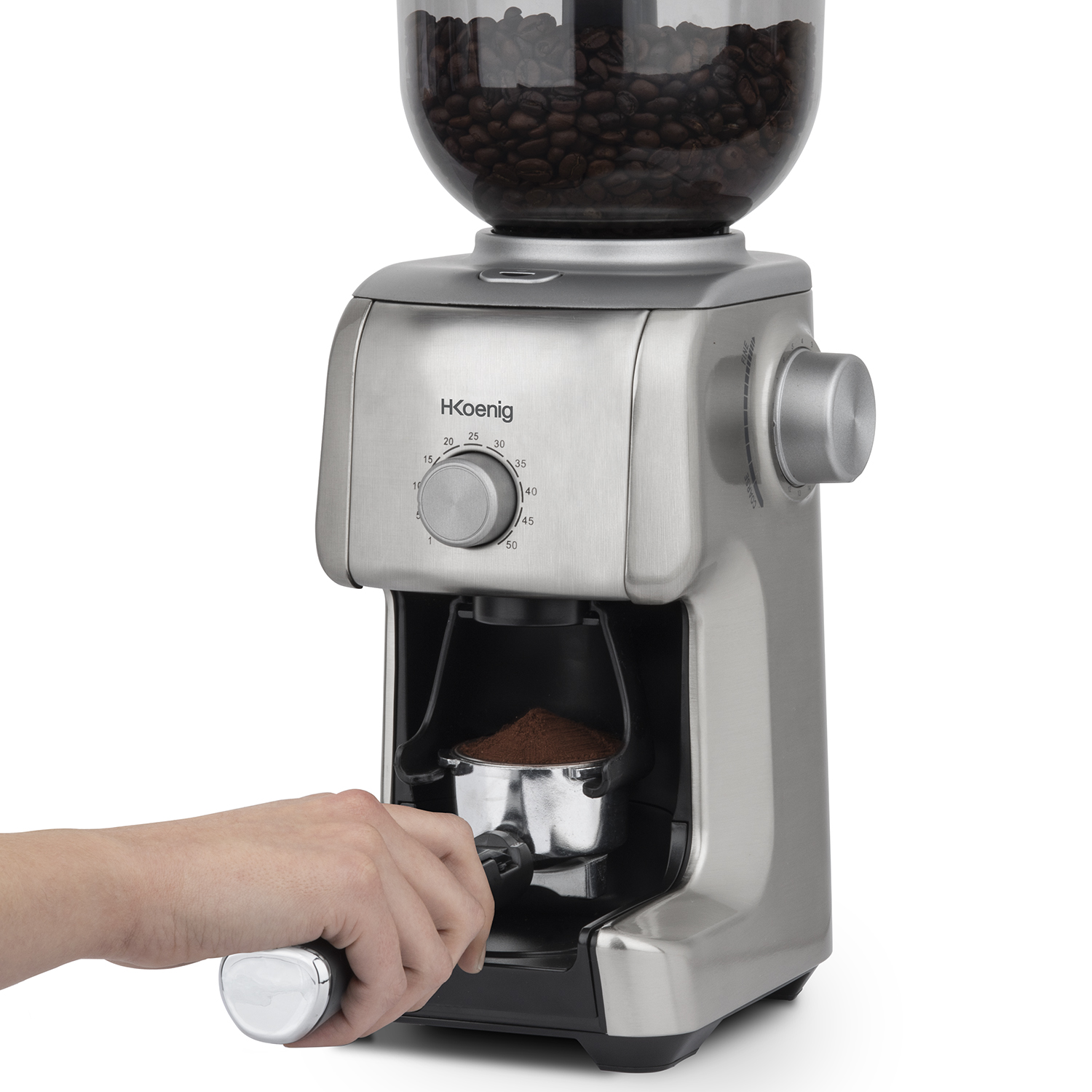 Macinacaffè argentato con chicchi e caffè macinato, mano che tiene il portafiltro.