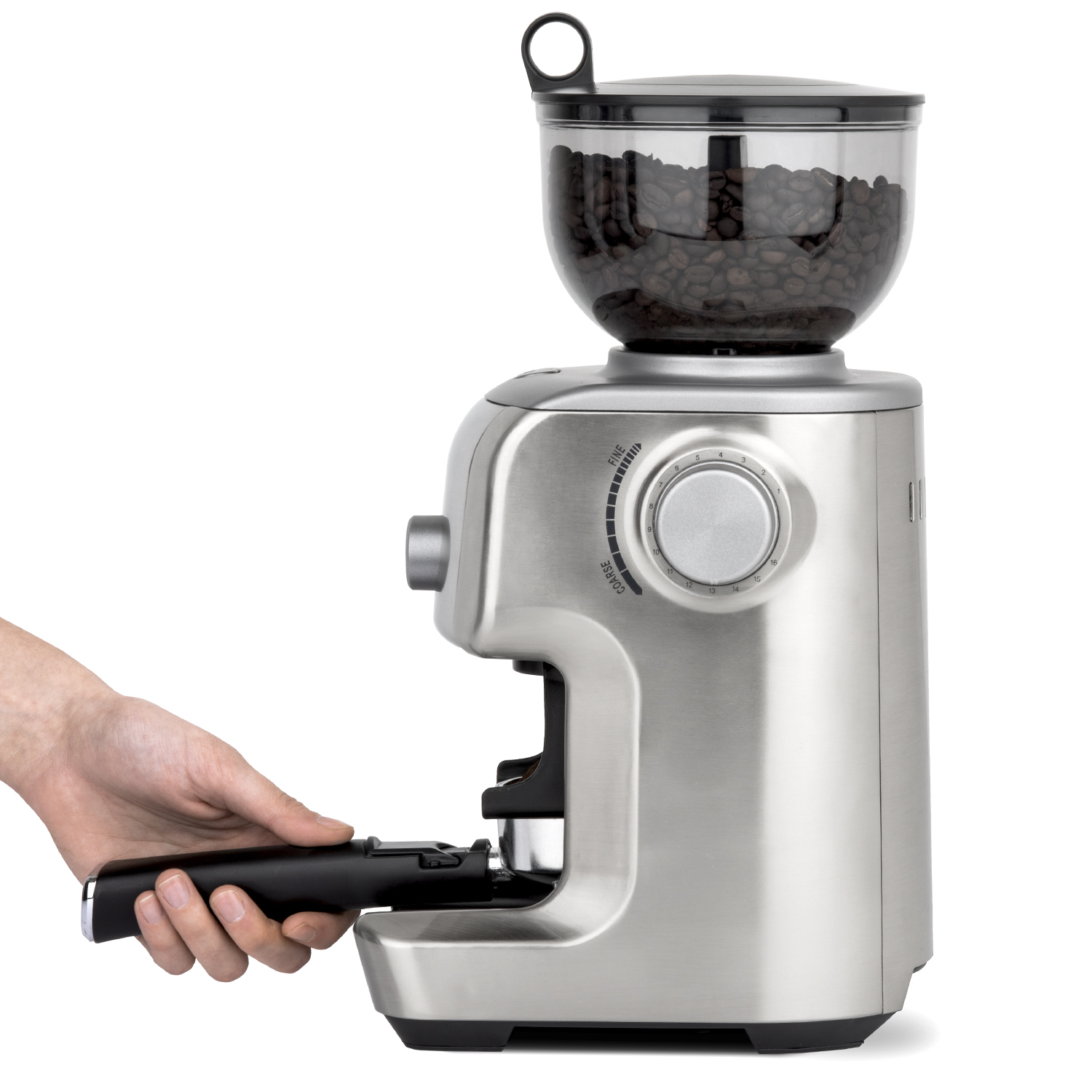 Un macinacaffè argentato con un contenitore trasparente per i chicchi. Una mano tiene il portafiltro.