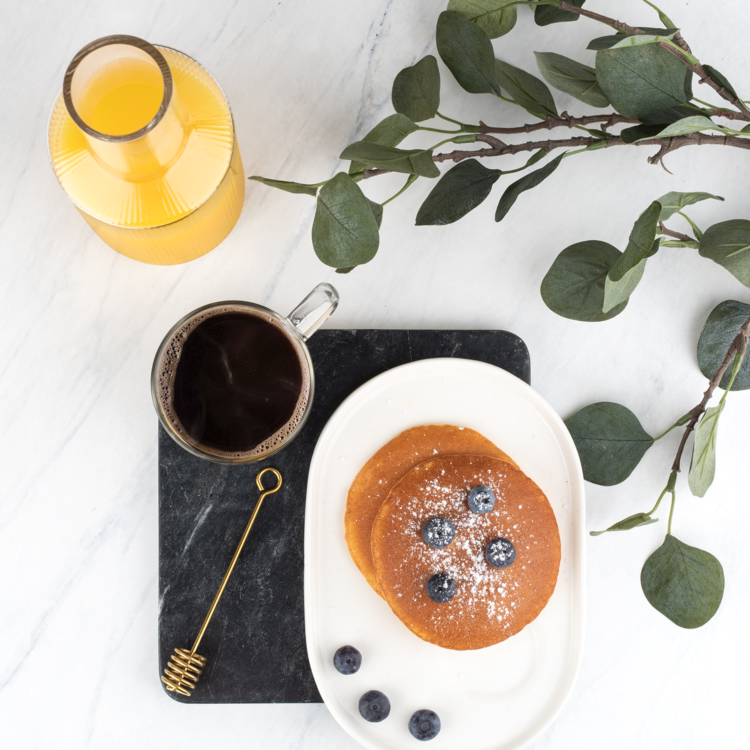 Frühstücksszene mit Pfannkuchen, Blaubeeren, Kaffee und Orangensaft. Weißer Marmorhintergrund.