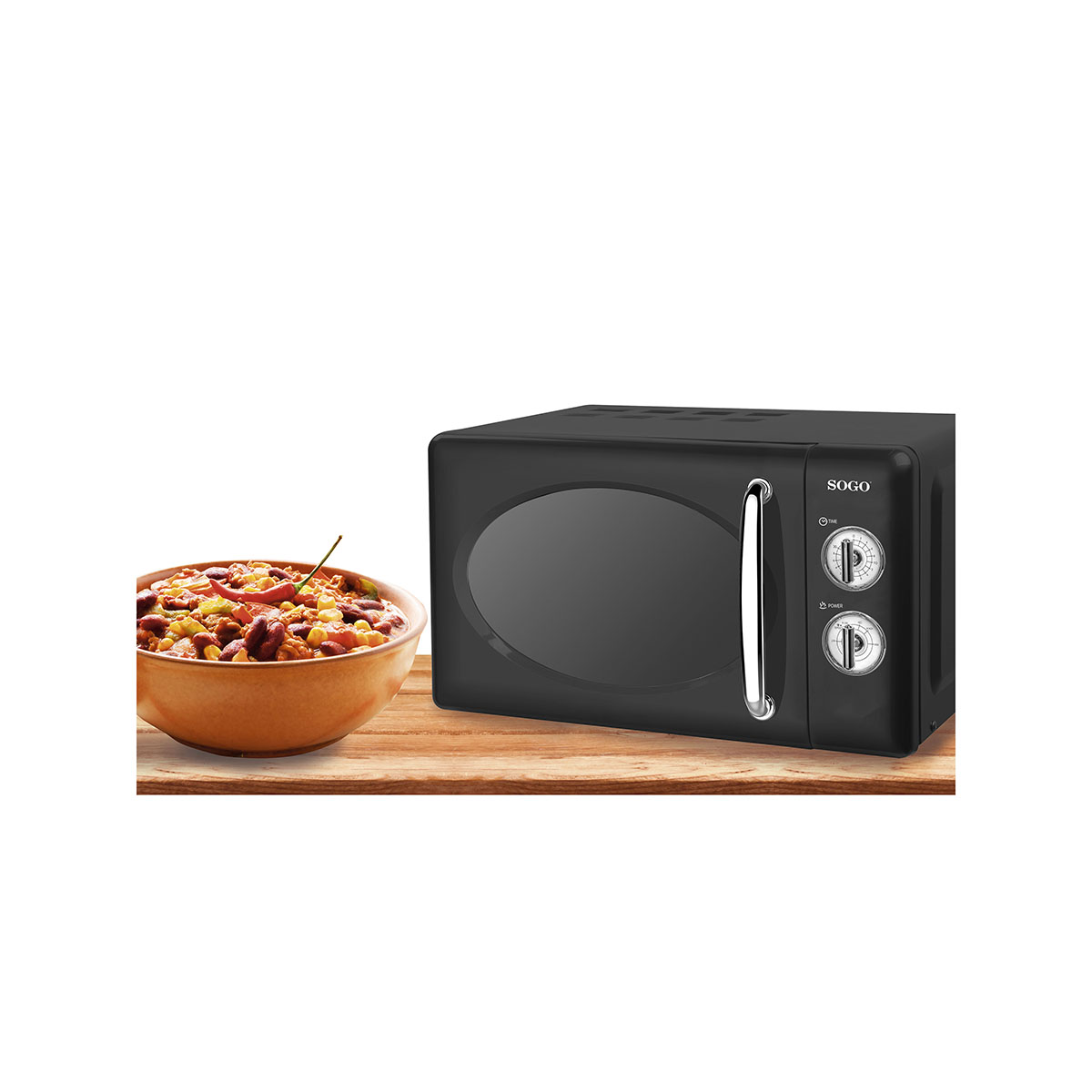Un microondas negro con un cuenco de chili junto a él sobre una superficie de madera.
