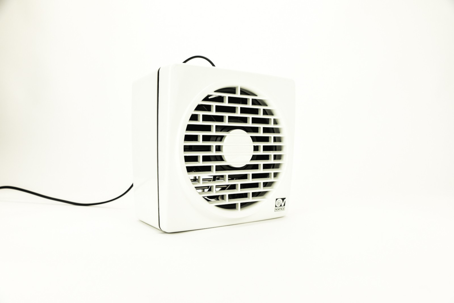 Weißer quadratischer Ventilator mit schwarzem Gitter und schwarzem Netzkabel. Weißer Hintergrund.