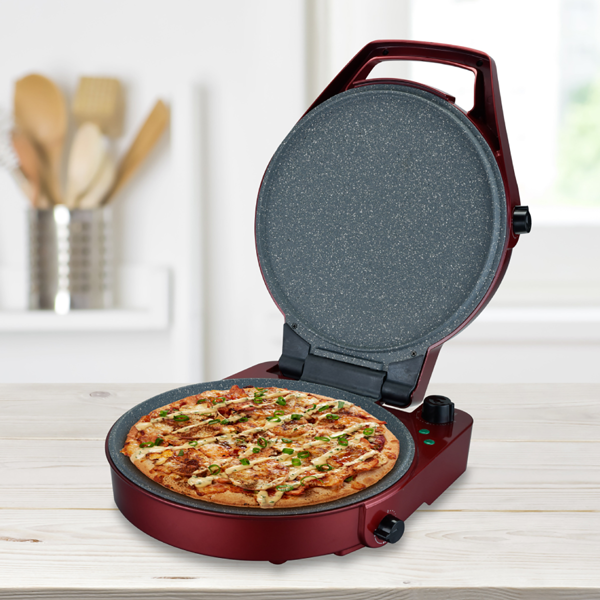 Máquina de pizza roja con pizza dentro, sobre una superficie de madera. Fondo de cocina.