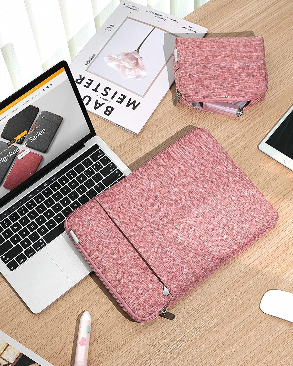 Rosa Laptop-Hülle auf einem Schreibtisch mit Laptop, Büchern und Stift. Sie hat einen Reißverschluss.