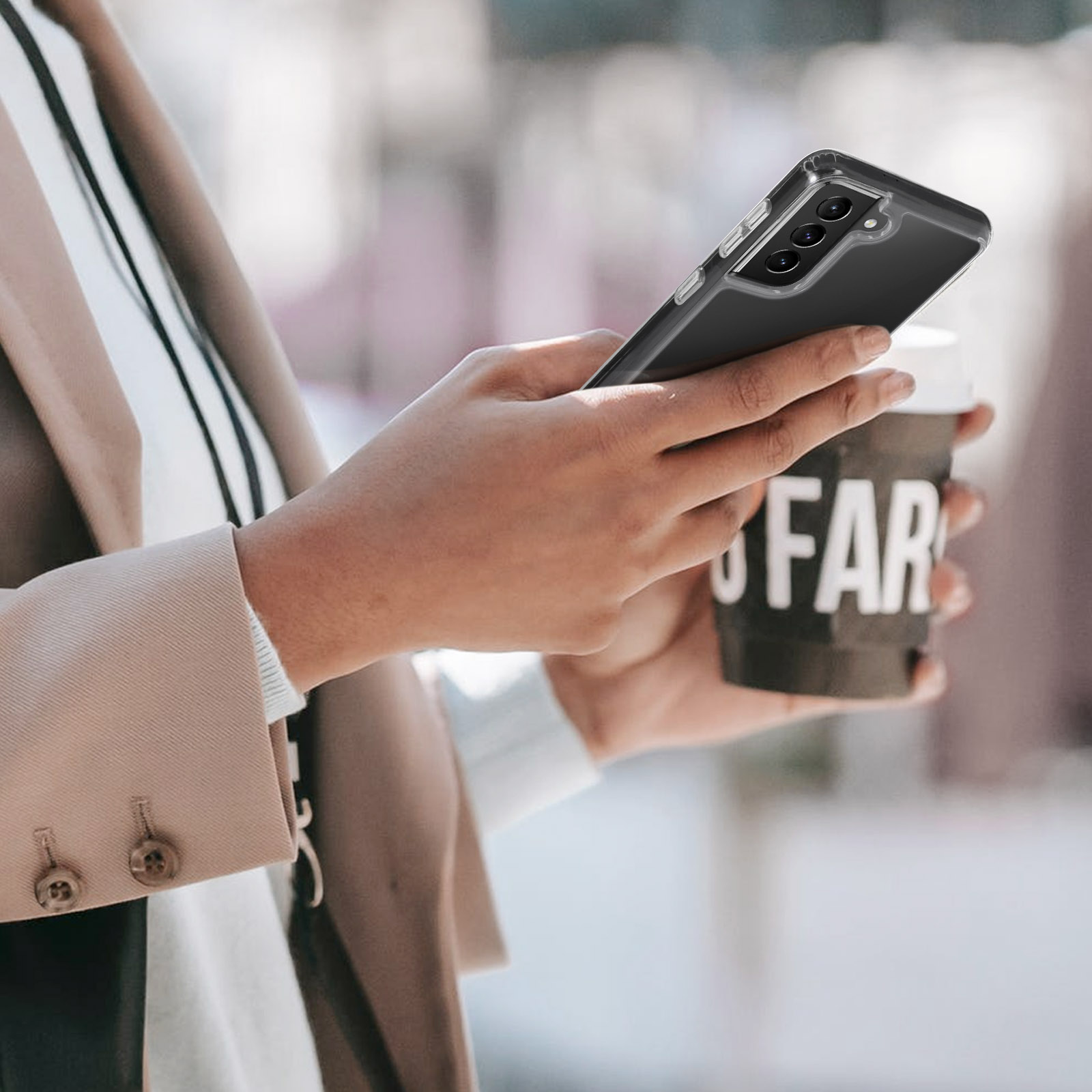 Una persona che tiene un telefono in una custodia trasparente e una tazza di caffè con la parola 'FAR' sopra.