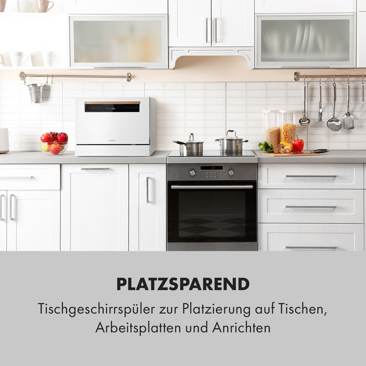 Weiße Küche mit Geschirrspüler, Backofen, Töpfen und Pfannen, und Gemüse auf der Theke.