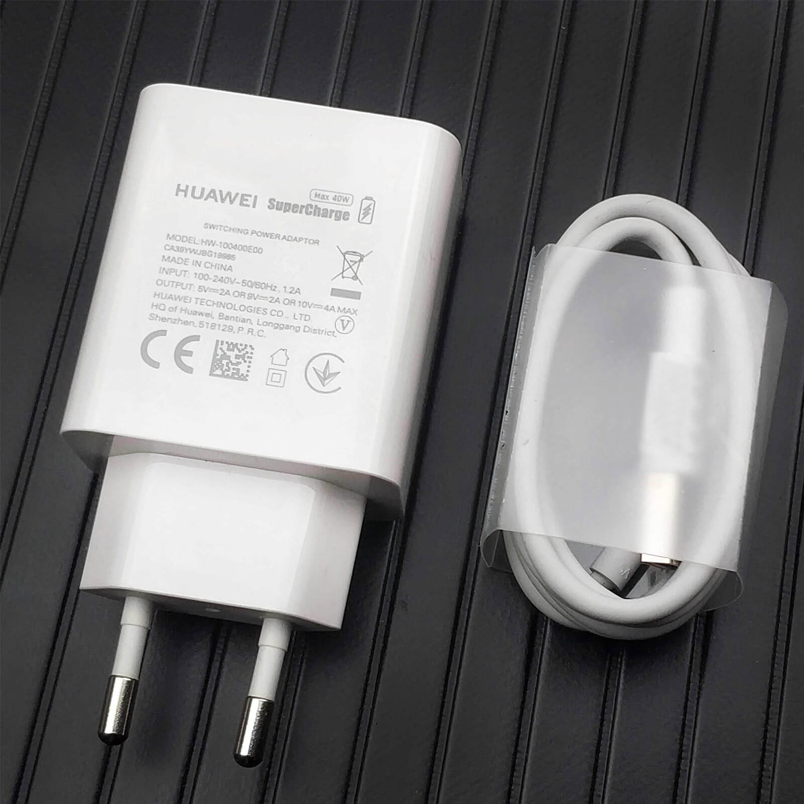Un caricatore Huawei SuperCharge bianco e un cavo di ricarica su una superficie.