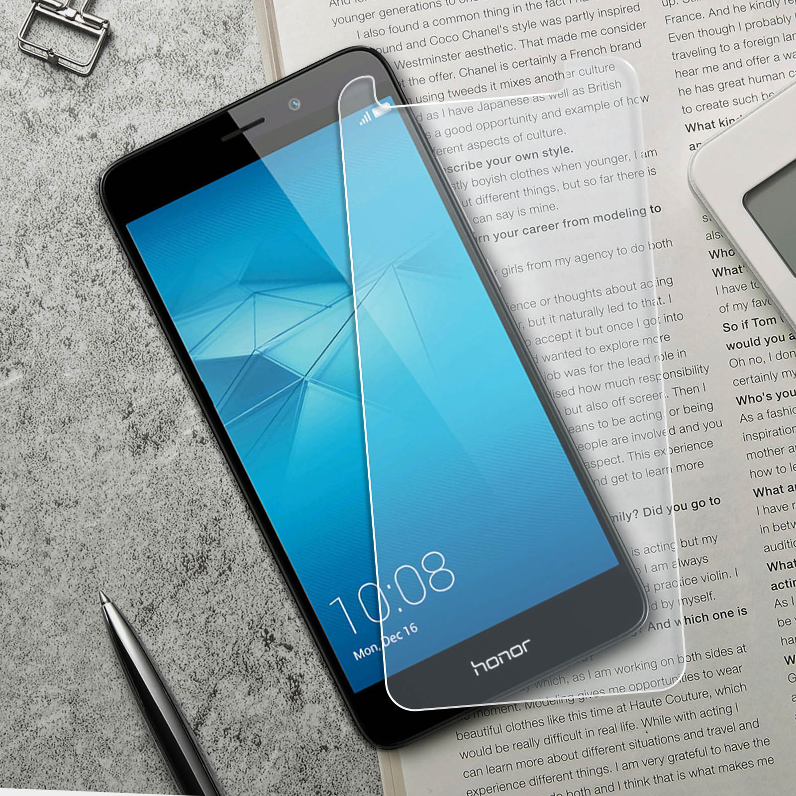 Un telefono con una protezione per lo schermo è su un tavolo vicino a una penna e dei fogli.