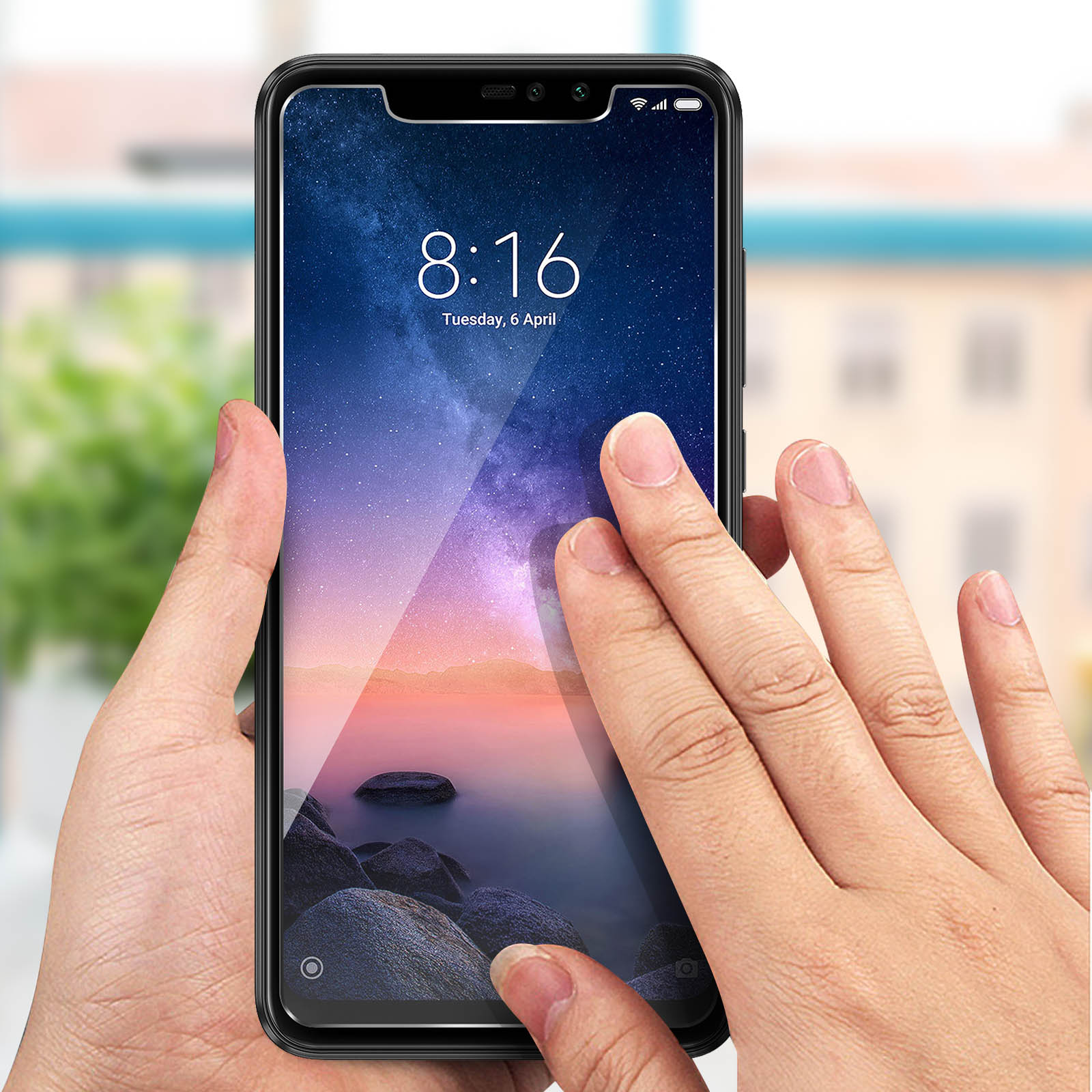 Mani che tengono uno smartphone con un proteggi schermo applicato.