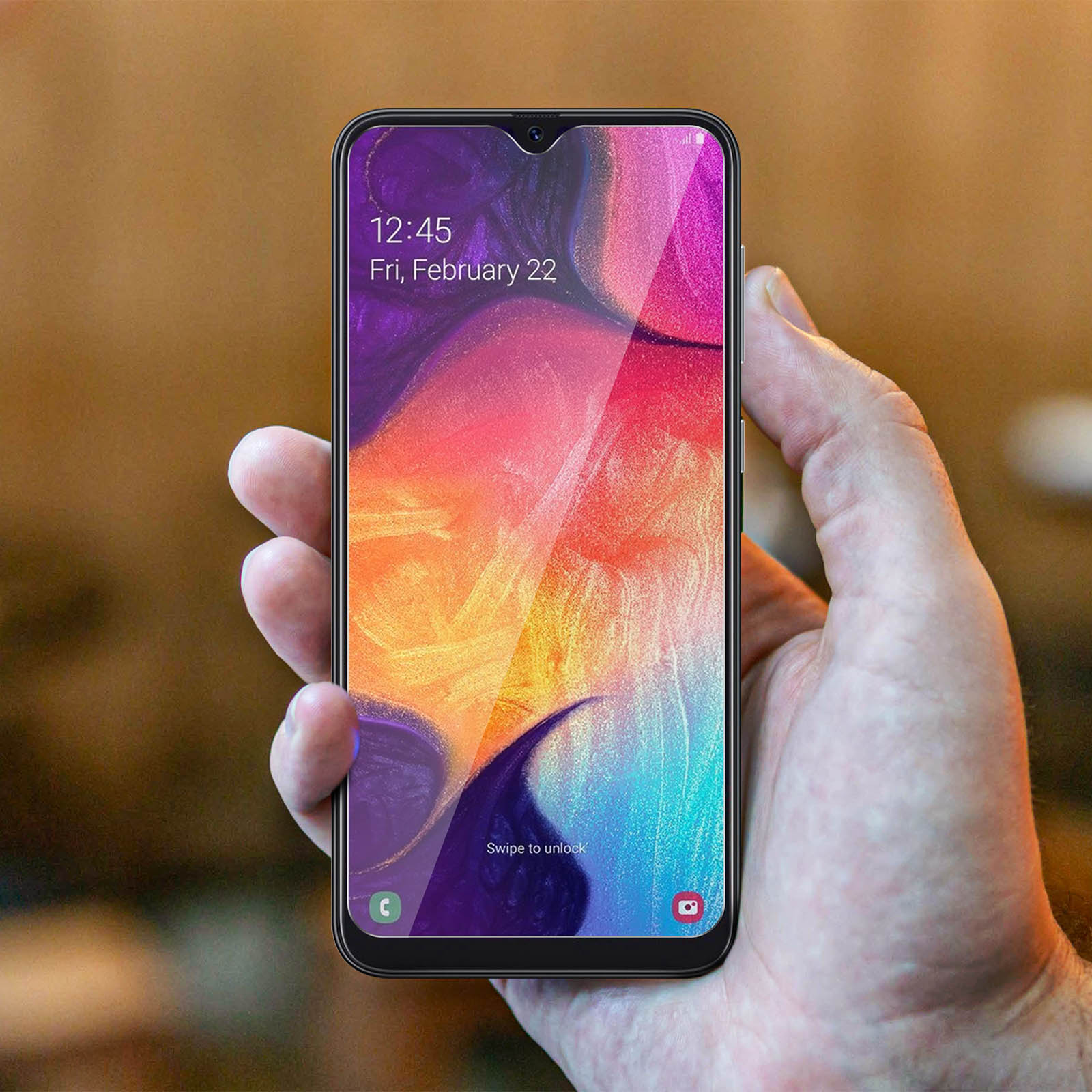 Mano che tiene un telefono con una protezione schermo applicata, con uno schermo colorato.