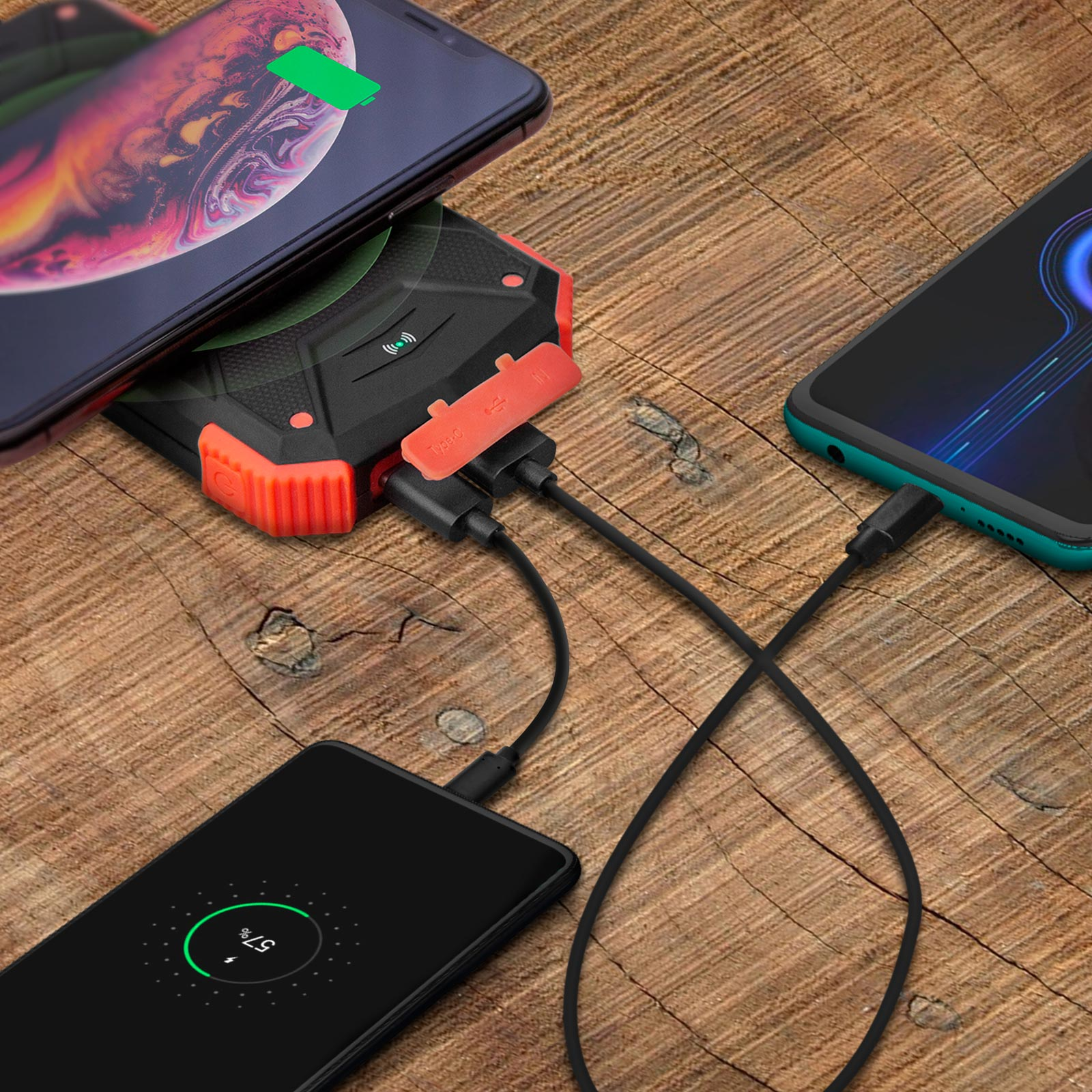 Drei Telefone, die von einer Powerbank auf einer Holzoberfläche geladen werden.
