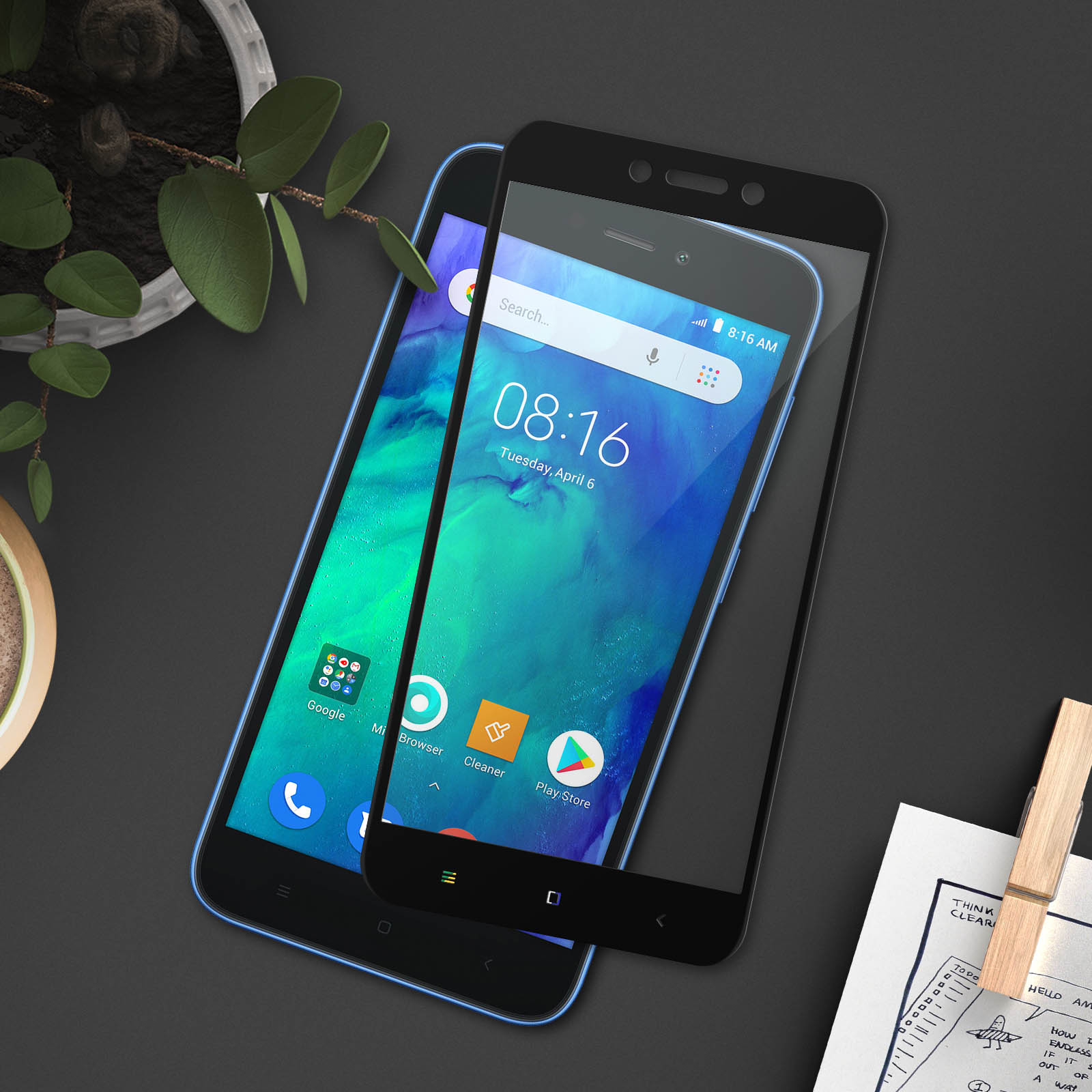 Due smartphone con protezioni. Un telefono mostra ora e data. Superficie nera.