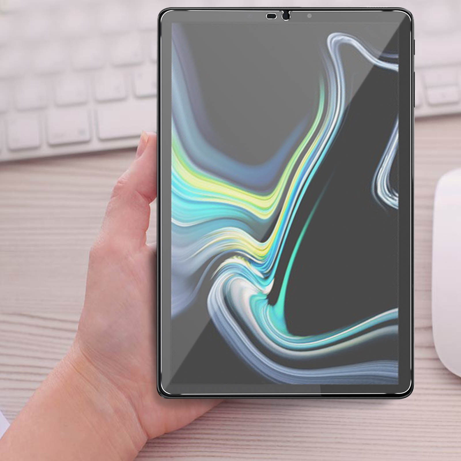 Persona che tiene in mano un tablet con protezione schermo applicata. Tastiera bianca visibile sullo sfondo.