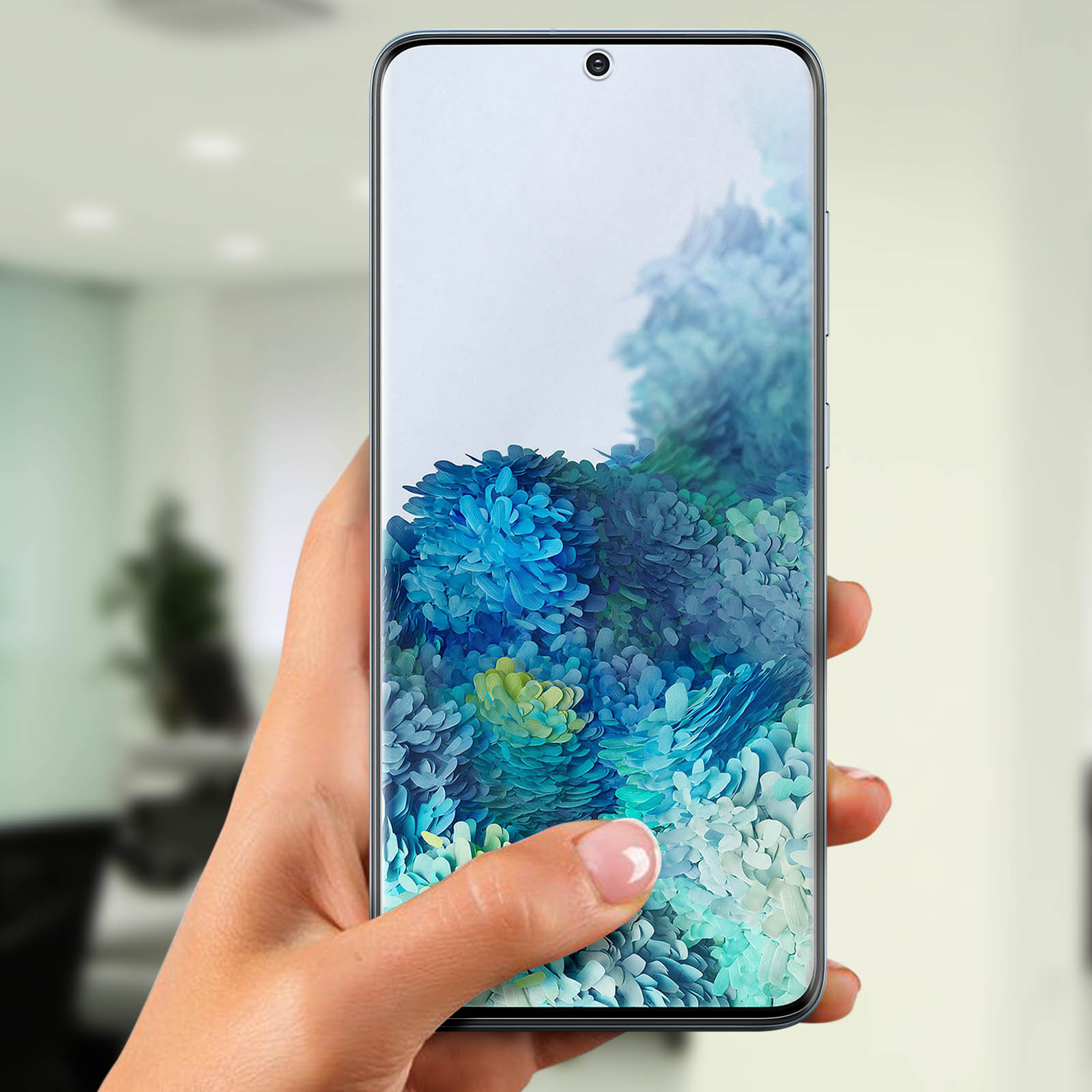 Una mano tiene un telefono con uno sfondo floreale. Lo sfondo è sfocato.