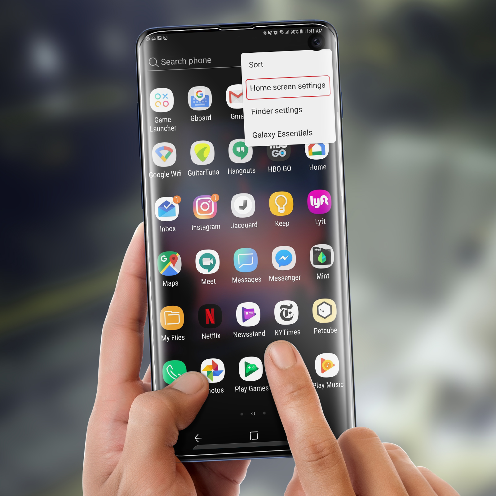 Una mano tocca lo schermo di un telefono che mostra icone di app e un menu. Sfondo sfocato.