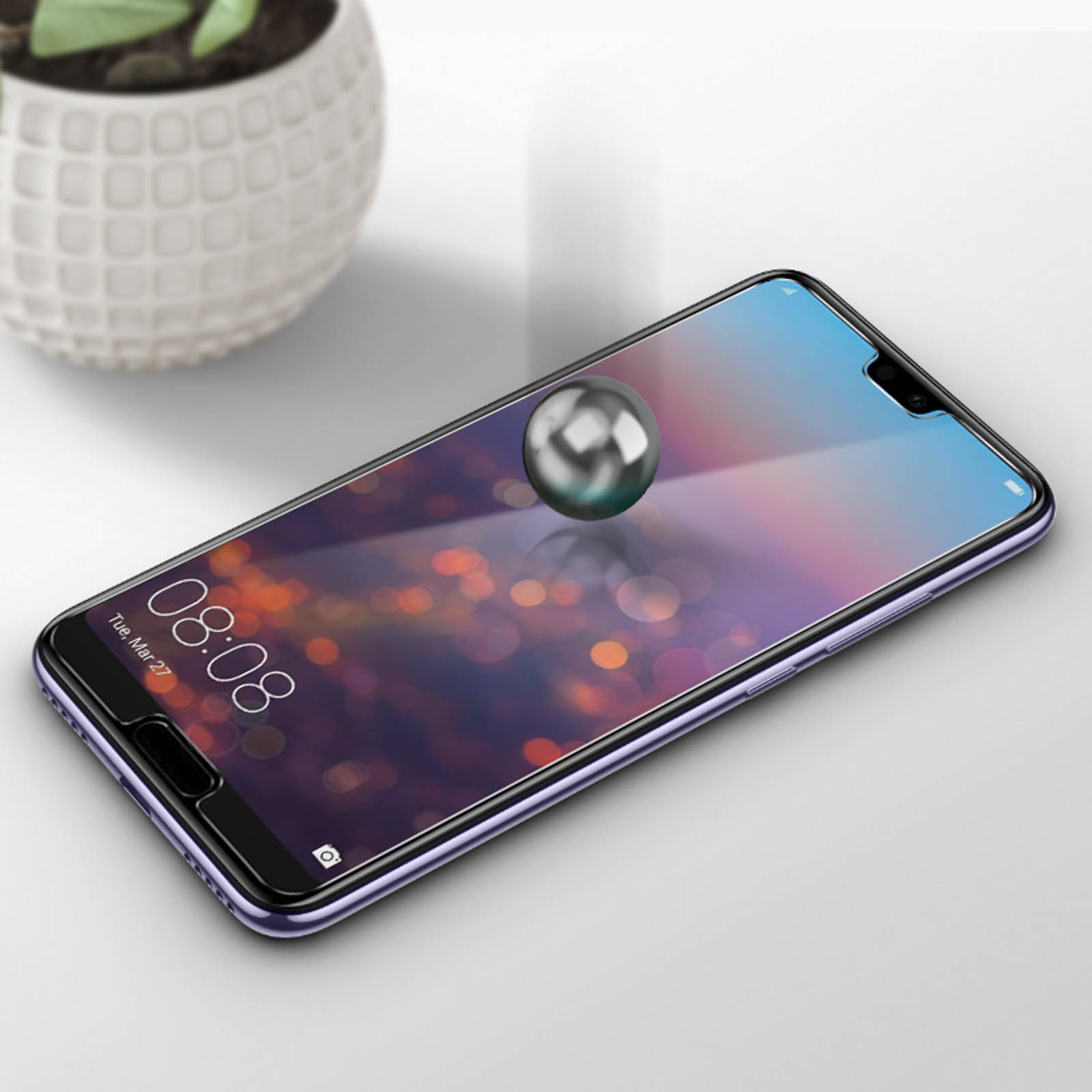 Telefono con protezione schermo su superficie bianca. Sfera metallica lucida fluttuante.