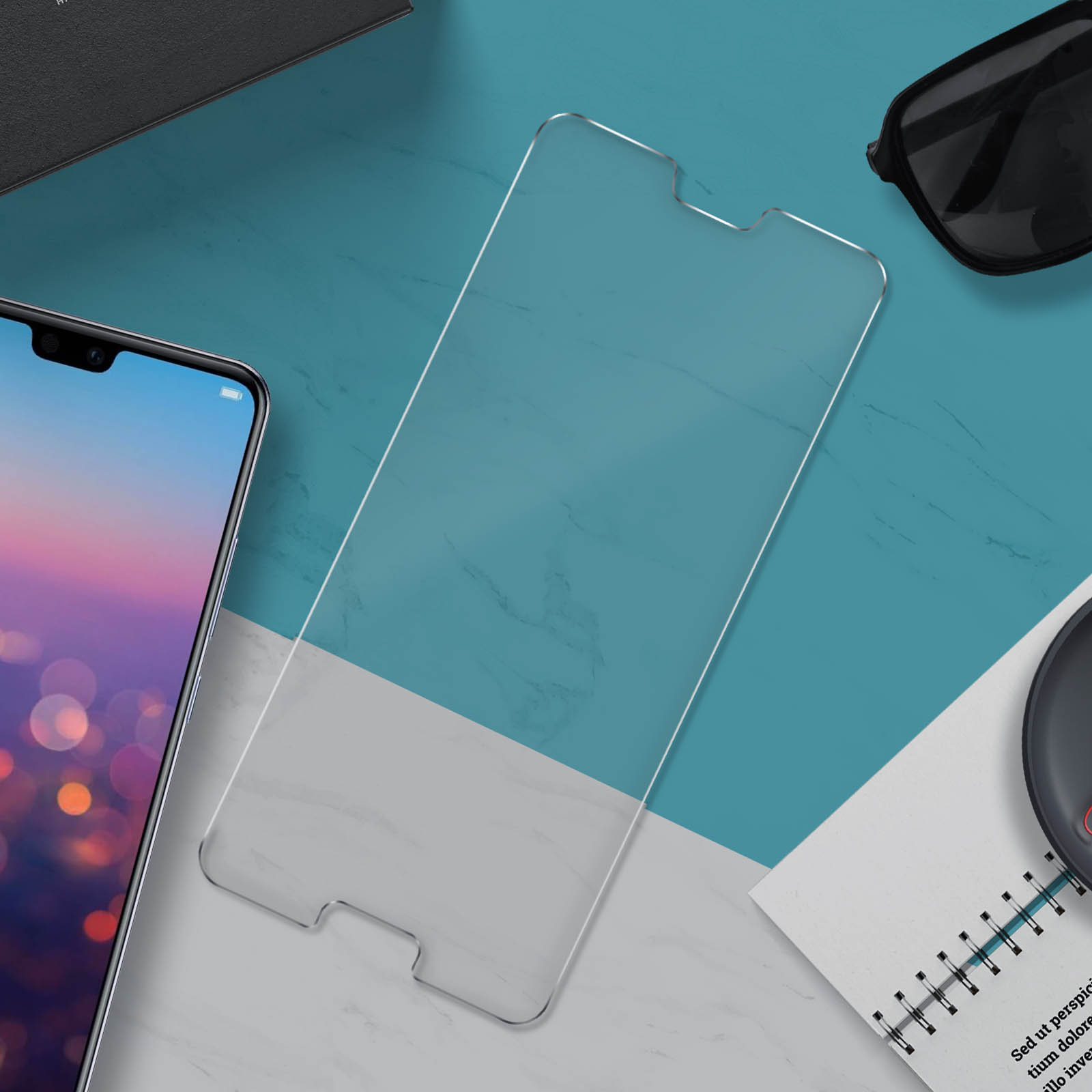 Un telefono e una protezione schermo su una superficie blu con un taccuino e occhiali da sole.
