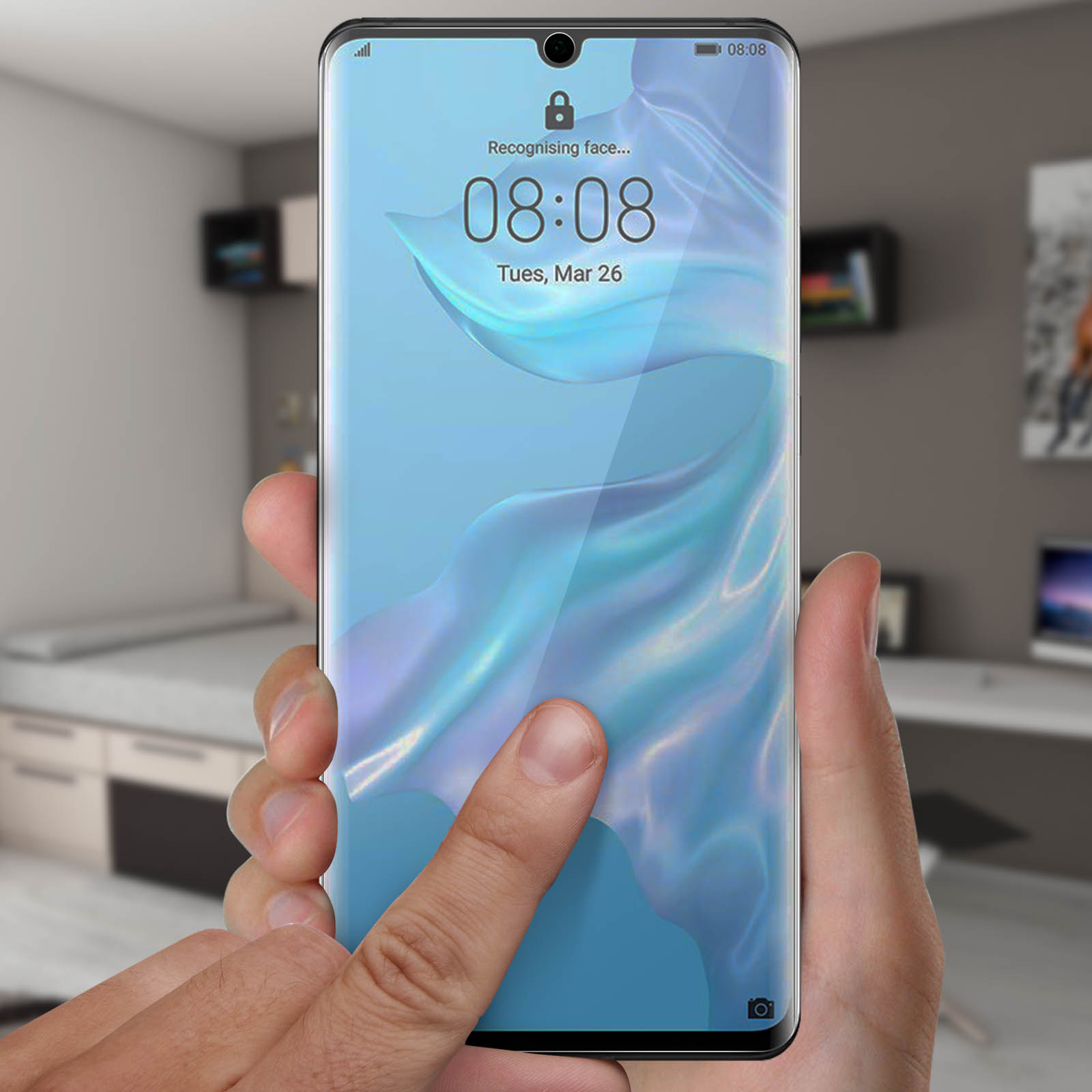 Una mano tocca lo schermo di un telefono con protezione. Il telefono mostra l'ora e la data.