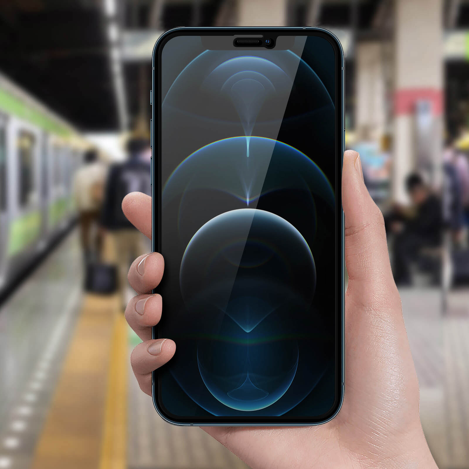 Mano che tiene un telefono con schermo blu, sfondo sfocato di una stazione ferroviaria.