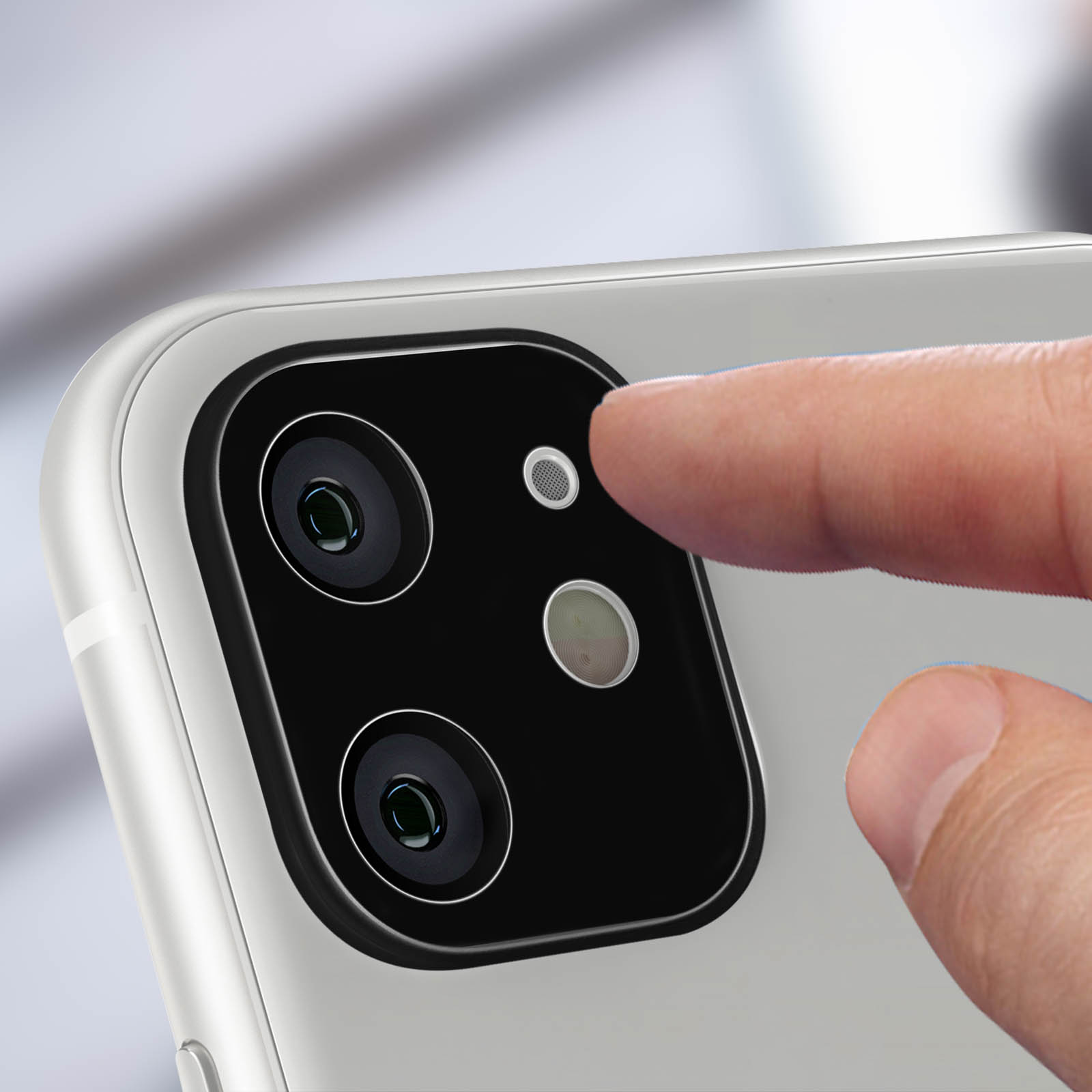 Primo piano del modulo fotocamera di uno smartphone con un dito che tocca l'obiettivo. Lenti nere e scocca bianca.