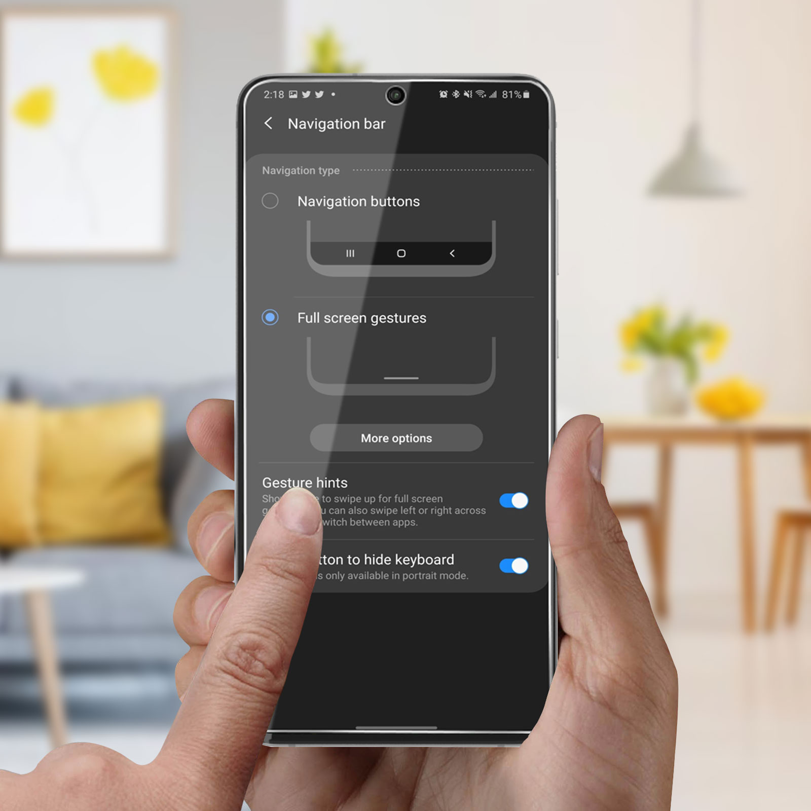 Una mano che tiene uno smartphone che mostra le impostazioni di navigazione. Lo schermo mostra i pulsanti di navigazione e i gesti a schermo intero.