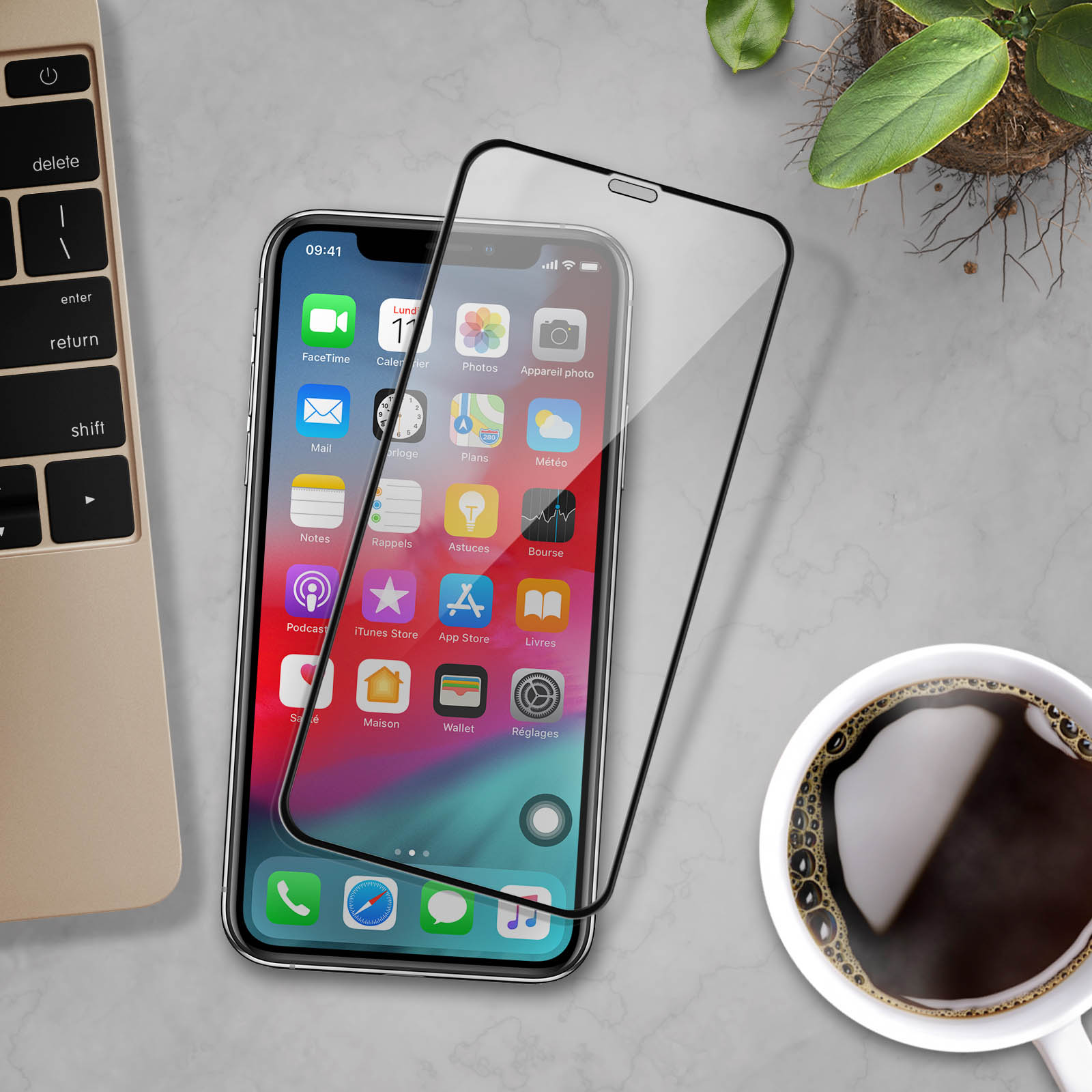 Un telefono con protezione schermo, vicino a tastiera e tazza di caffè. Pianta vicina. Superficie in marmo.