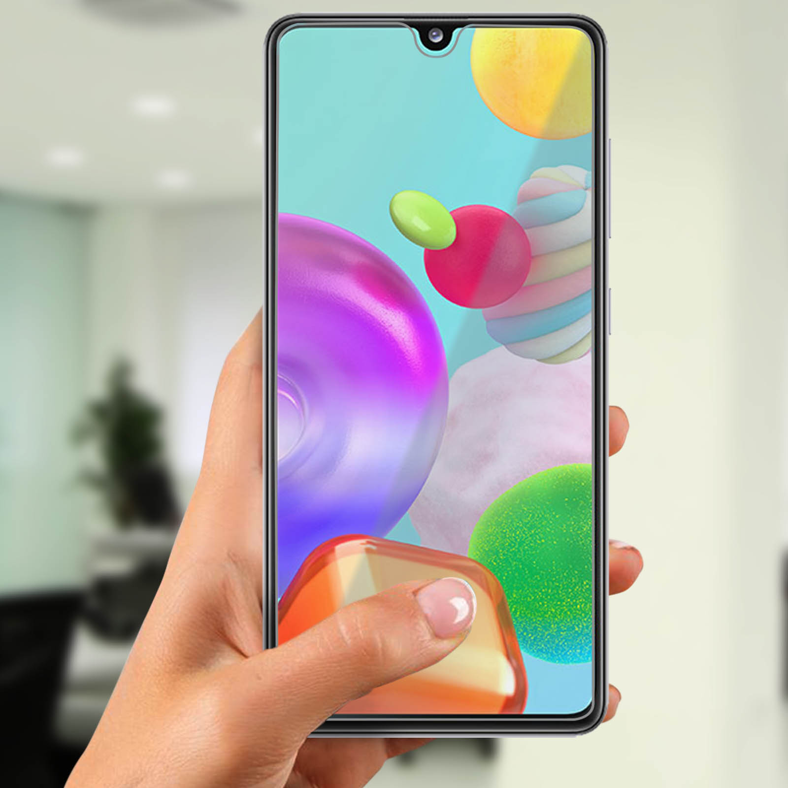 Una mano che tiene un telefono. Lo schermo mostra forme astratte colorate. Un dito tocca lo schermo.