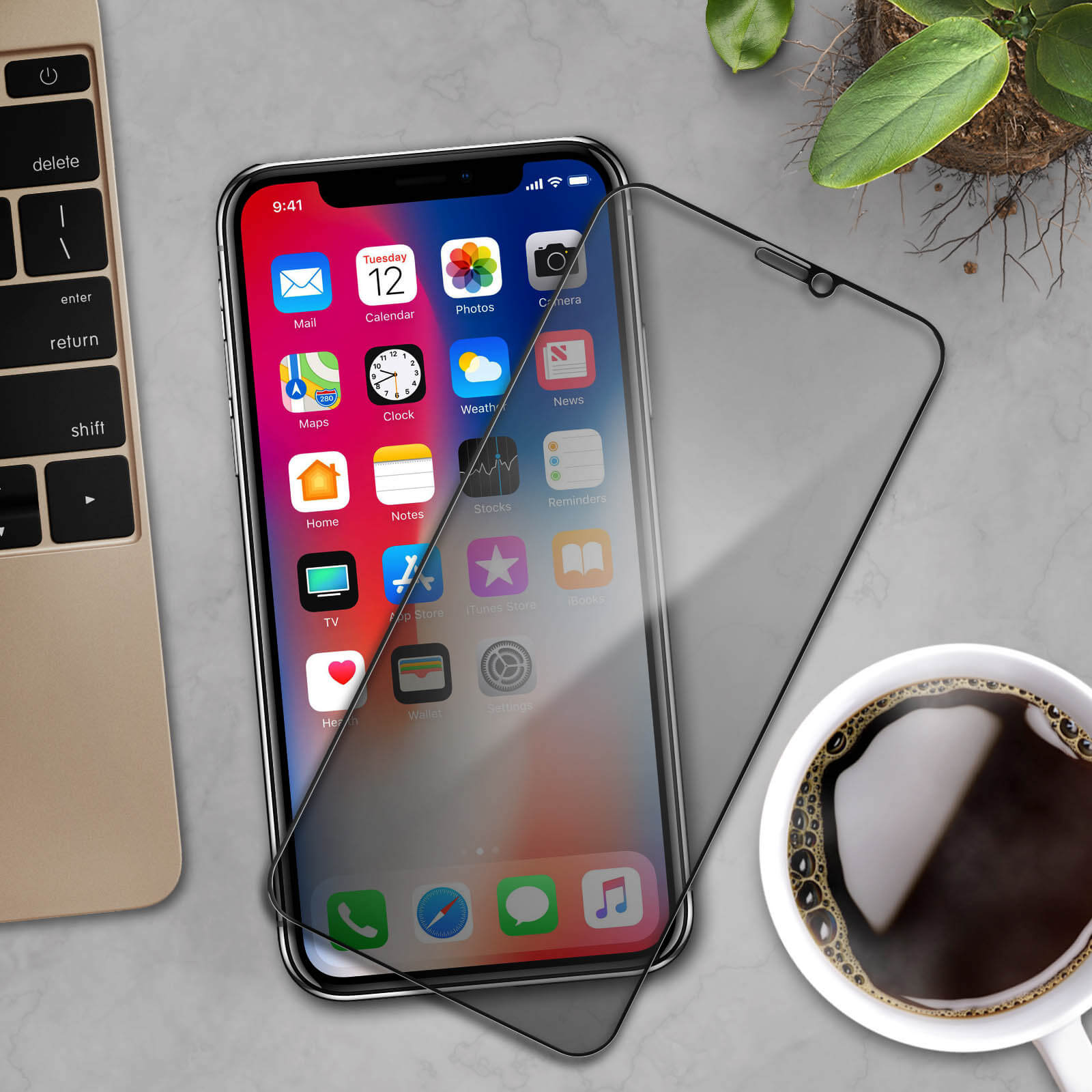 iPhone con protezione schermo, tastiera e tazza di caffè su superficie grigia.