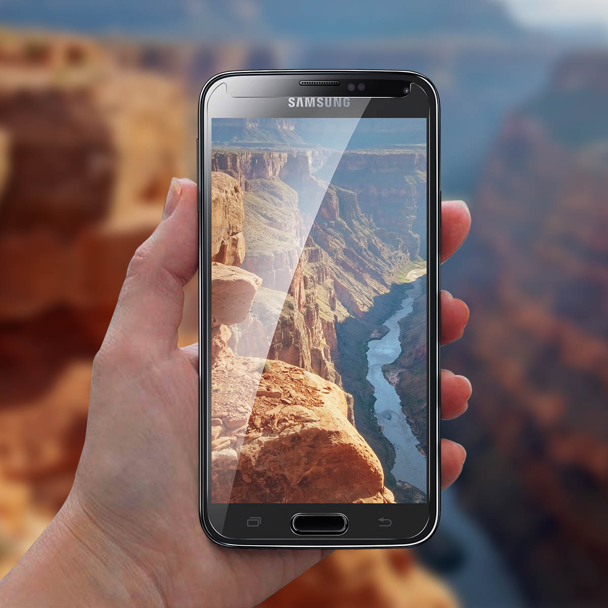Mano che tiene un telefono con uno sfondo panoramico di un canyon.