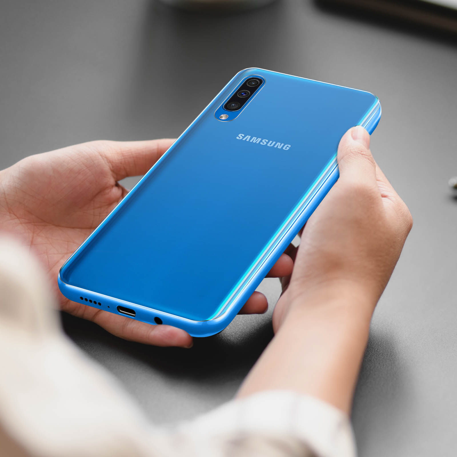 Una persona tiene in mano uno smartphone Samsung blu. Il retro del telefono è visibile, mostrando la fotocamera e il marchio.