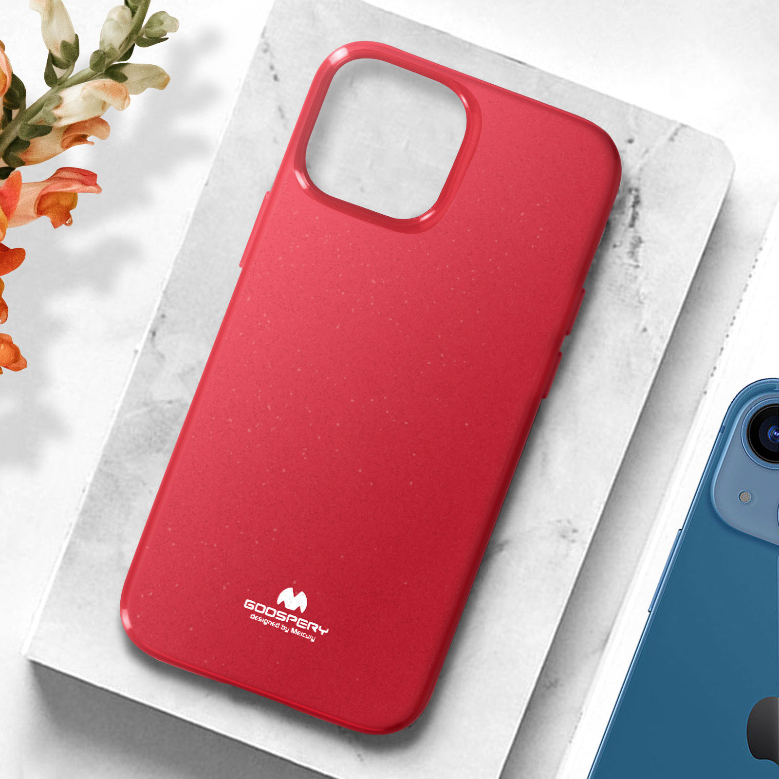 Custodia rossa per telefono su superficie di marmo bianco, con telefono blu e fiori visibili.