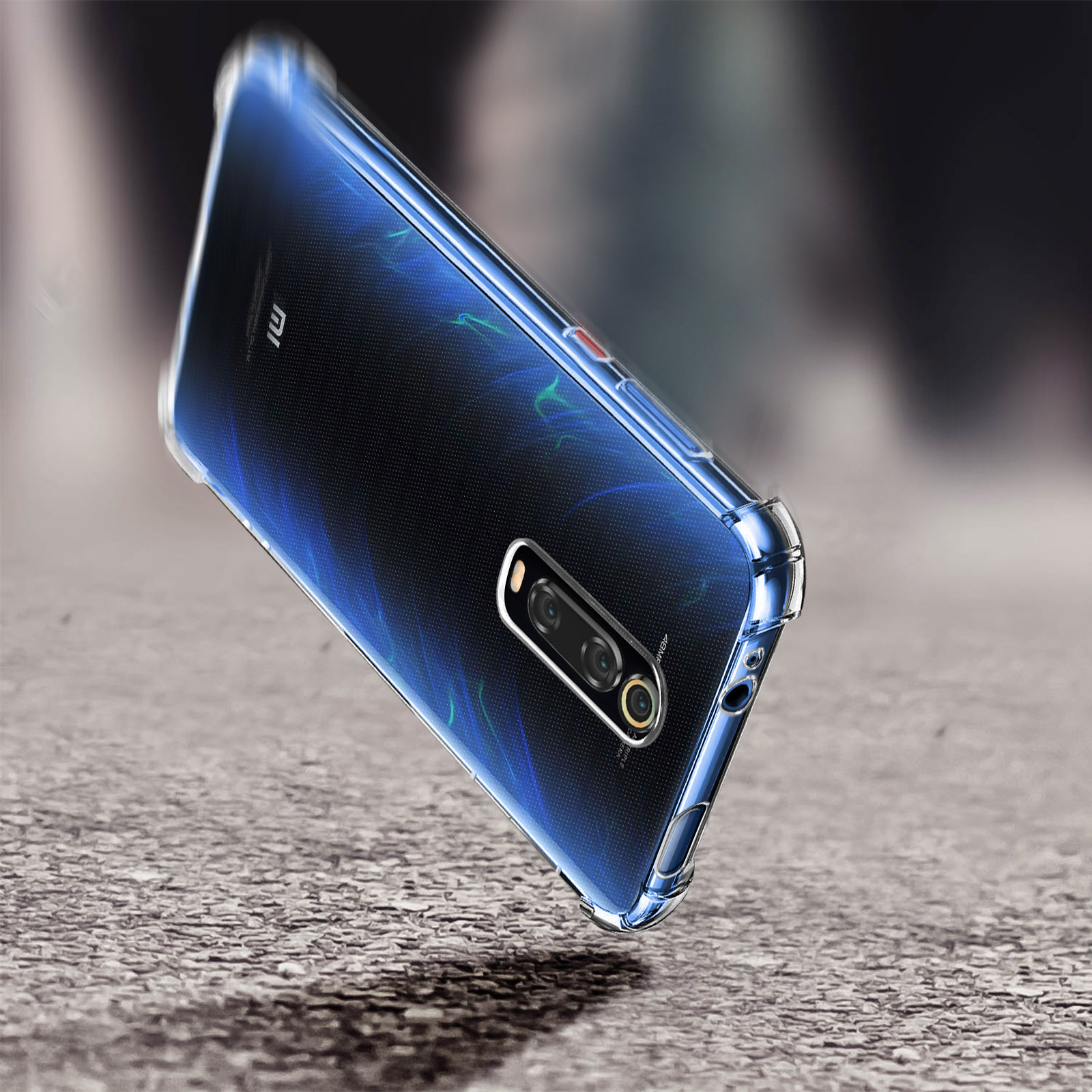 Un telefono nero, in una custodia trasparente, sta cadendo su una superficie grigia e strutturata.