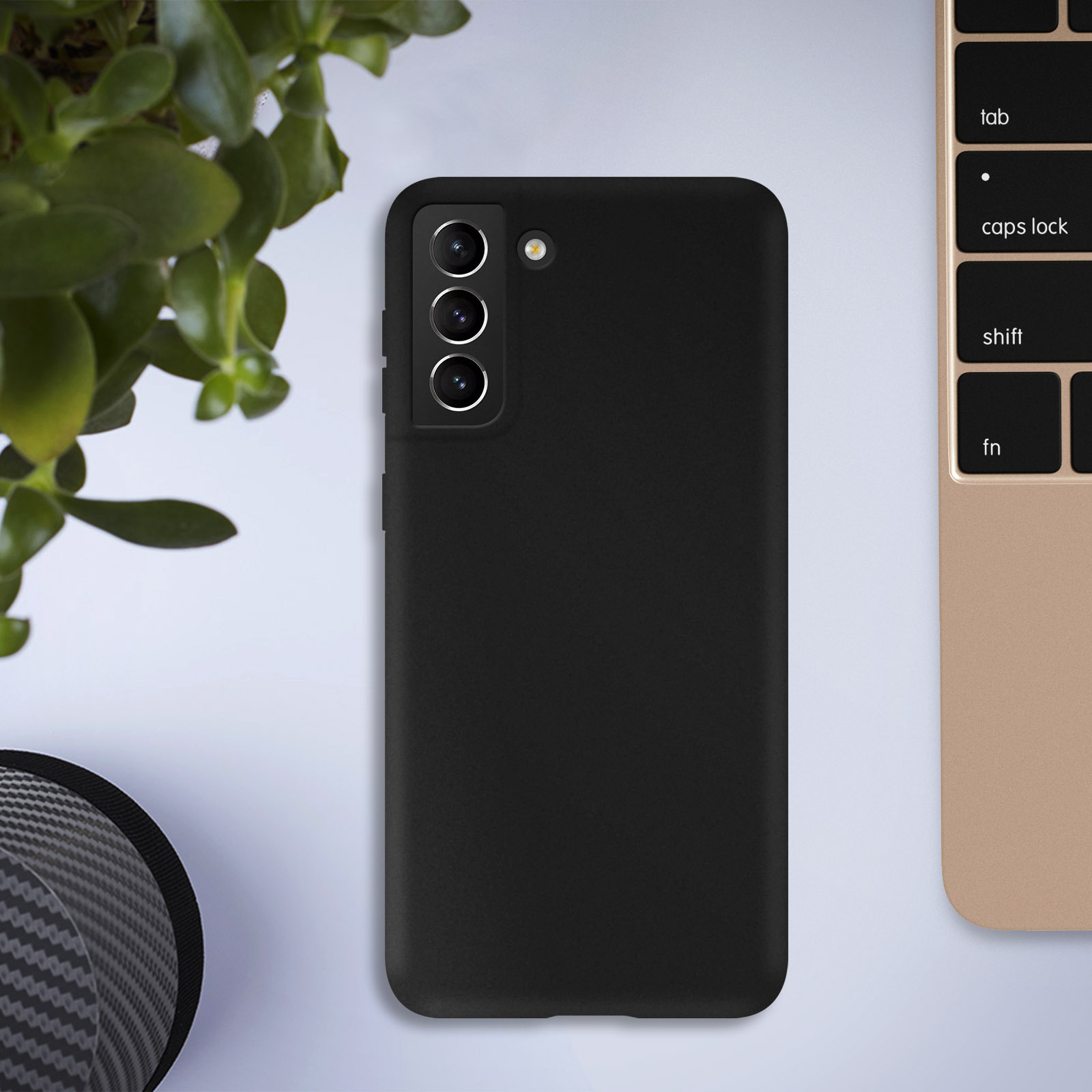 Coque de téléphone noire sur une table, plante verte en arrière-plan.